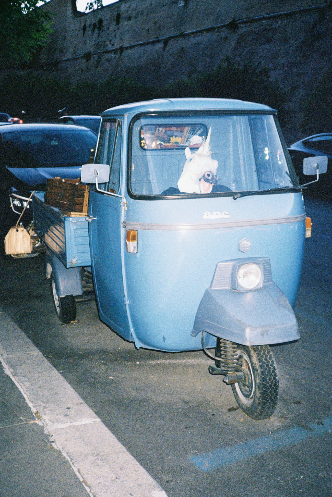A portrait photo of a unicorn’s head inside a parked three-wheel van, shot by Coco Torres