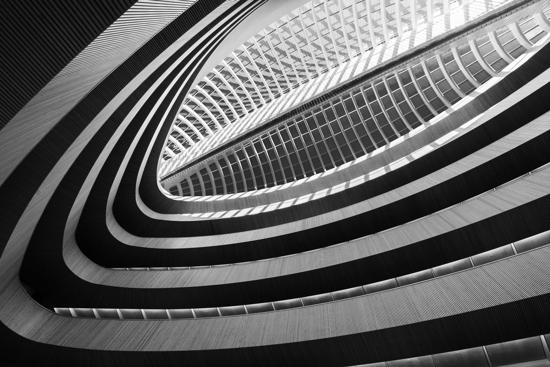 Photo en noir et blanc de l'intérieur d'un bâtiment à plusieurs étages, prise d'un angle bas vers le plafond, photo de Maike Jarsetz