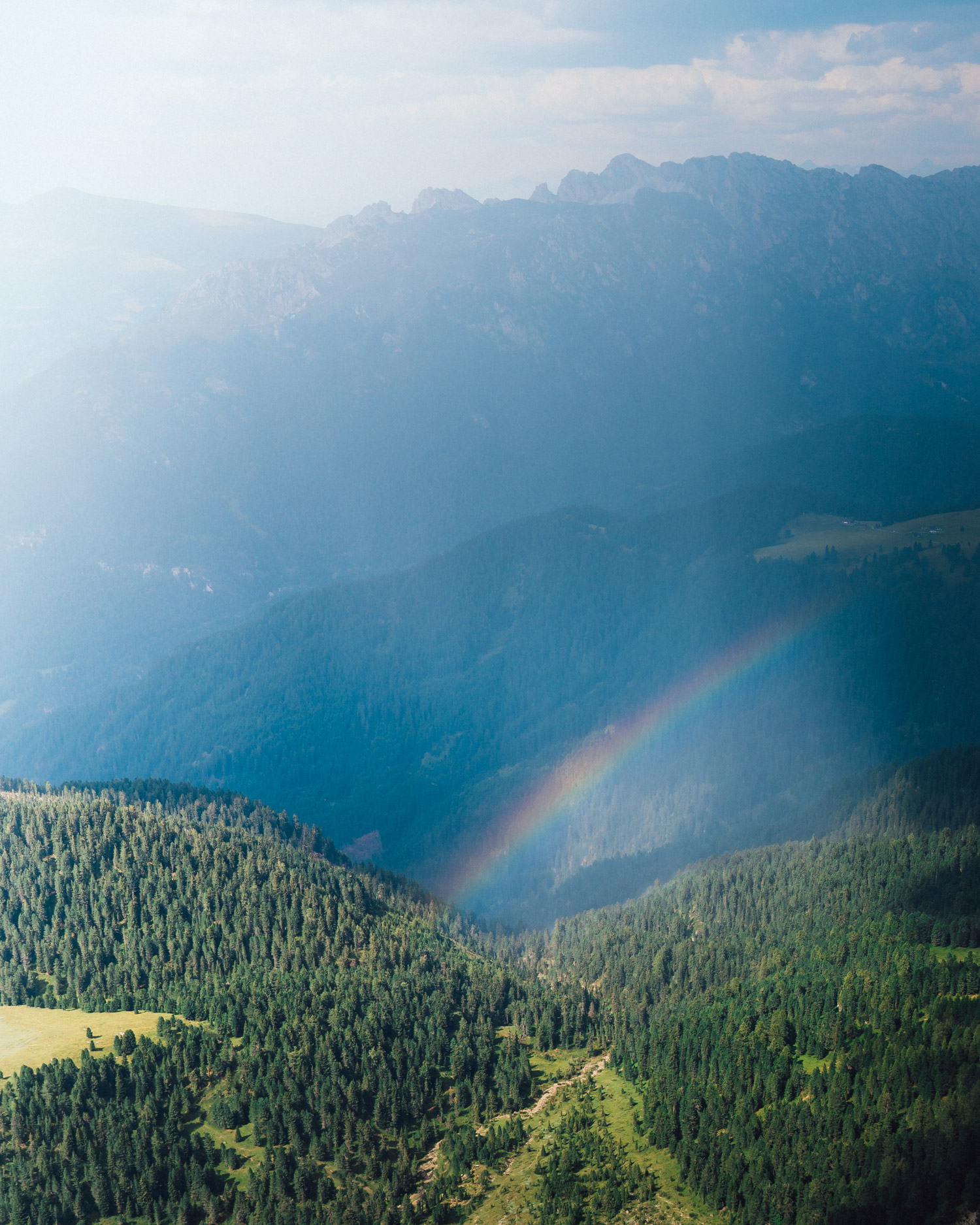 A valley with trees, mountains and a rainbow in the background. Shot by Jacob Murray with the Sony A7 IV and Sigma 35mm f/1.4 DG DN ART.