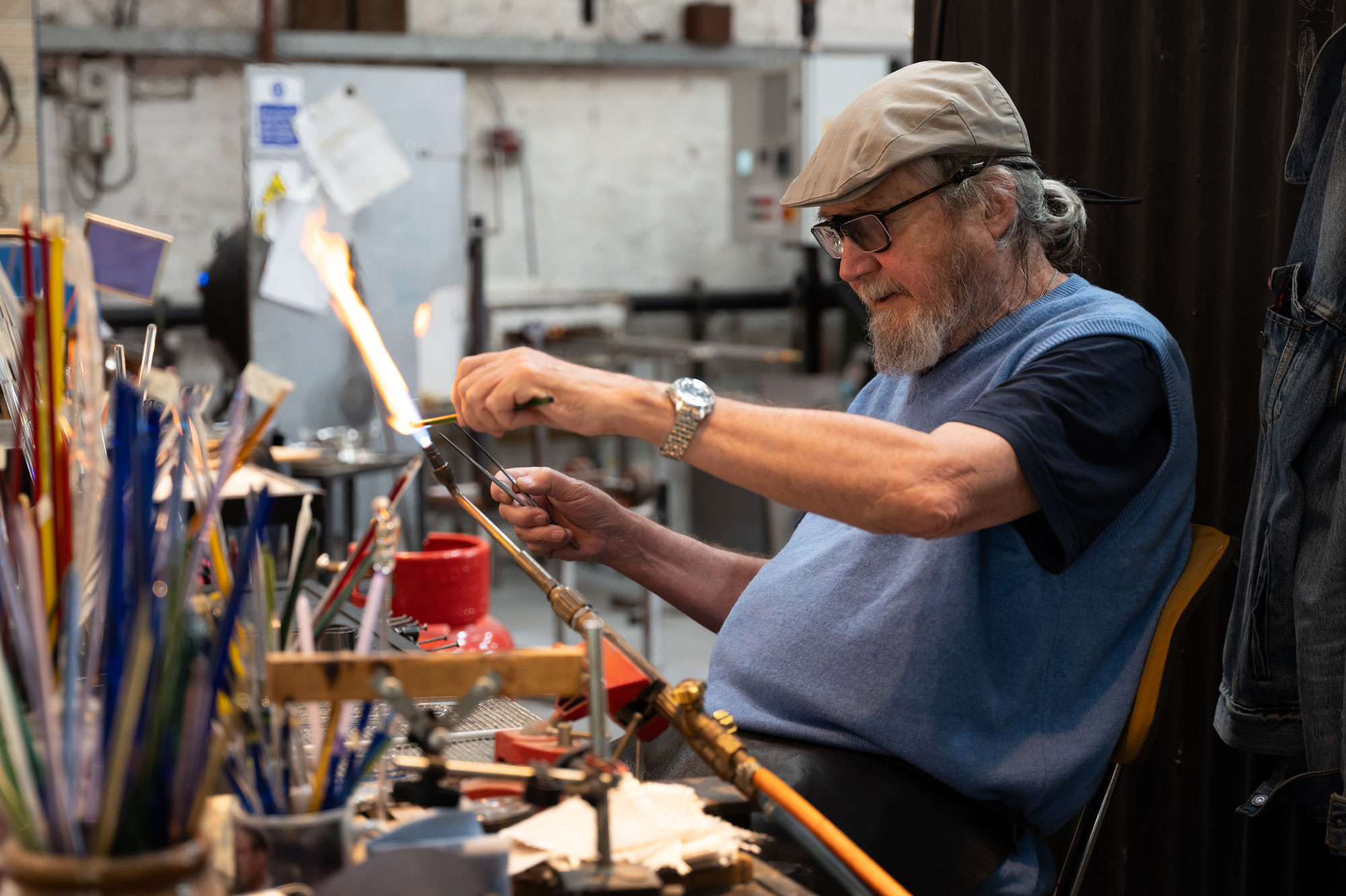 A person blows glass in their studio using a Bunsen burner with an open flame. Photo by Amy Moore with the Panasonic S1R I
