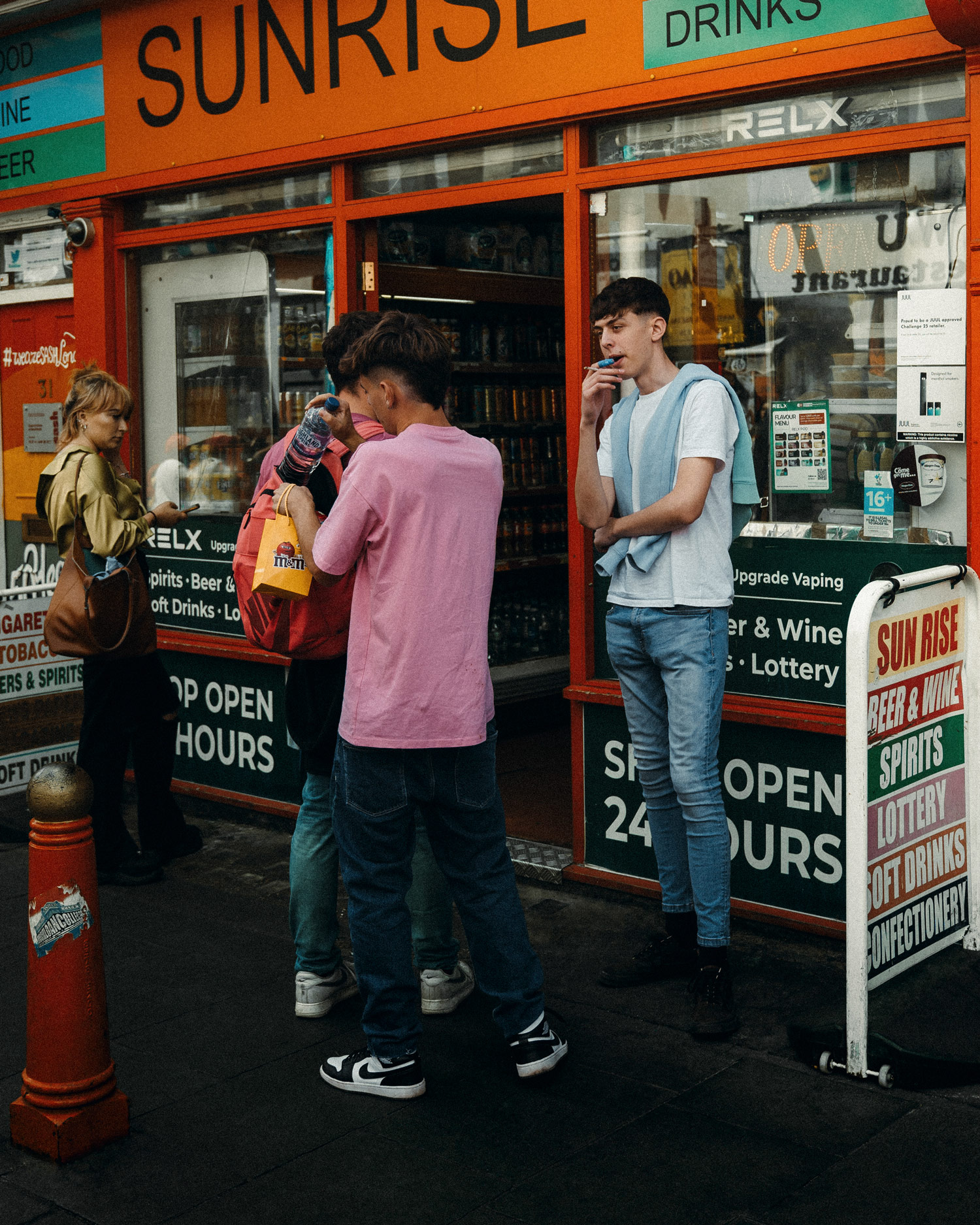 Four people stand outside a newsagent called Sunrise.