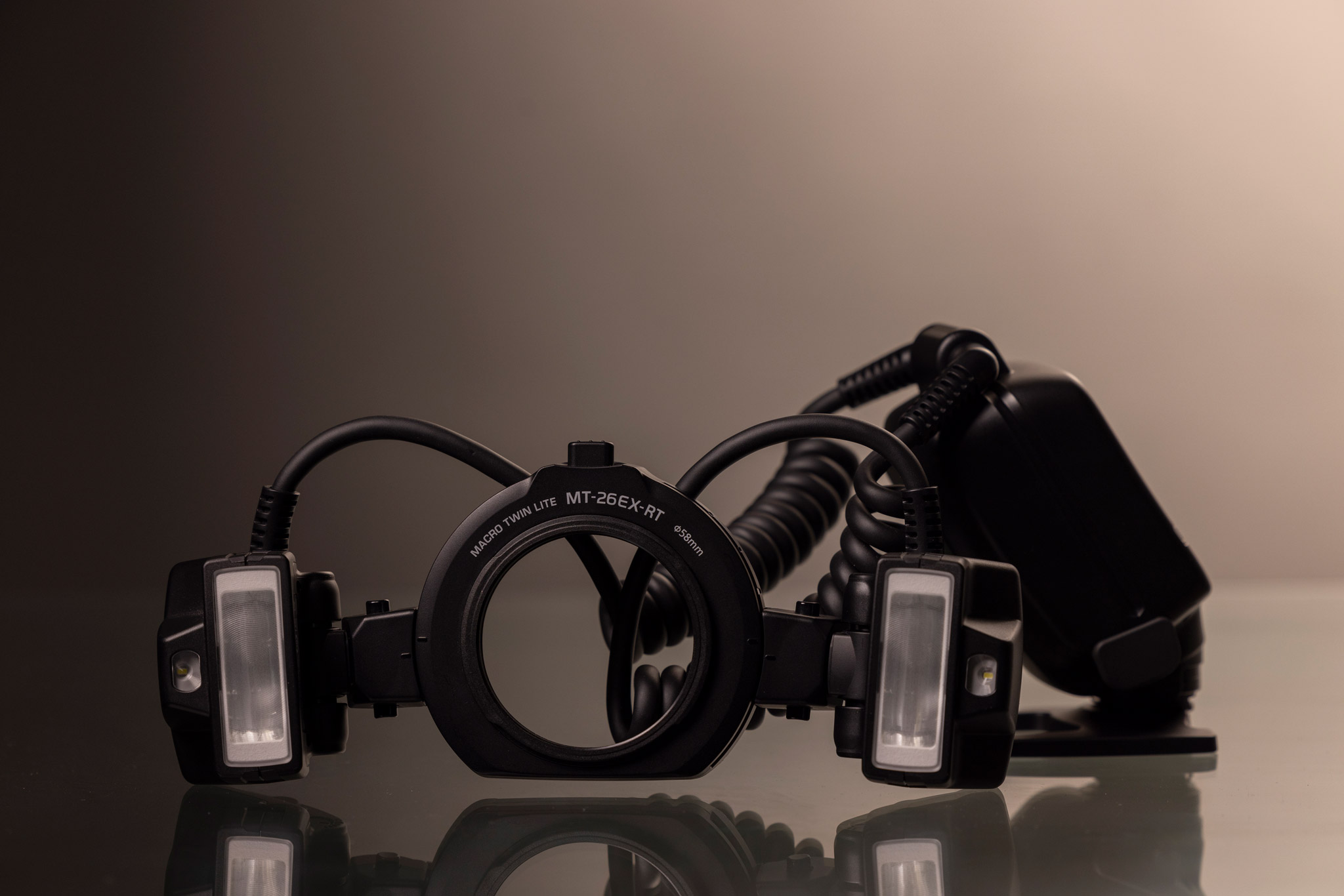 Le Canon Macro Twin Lite MT-26EX-RT posé devant un fond noir et blanc.