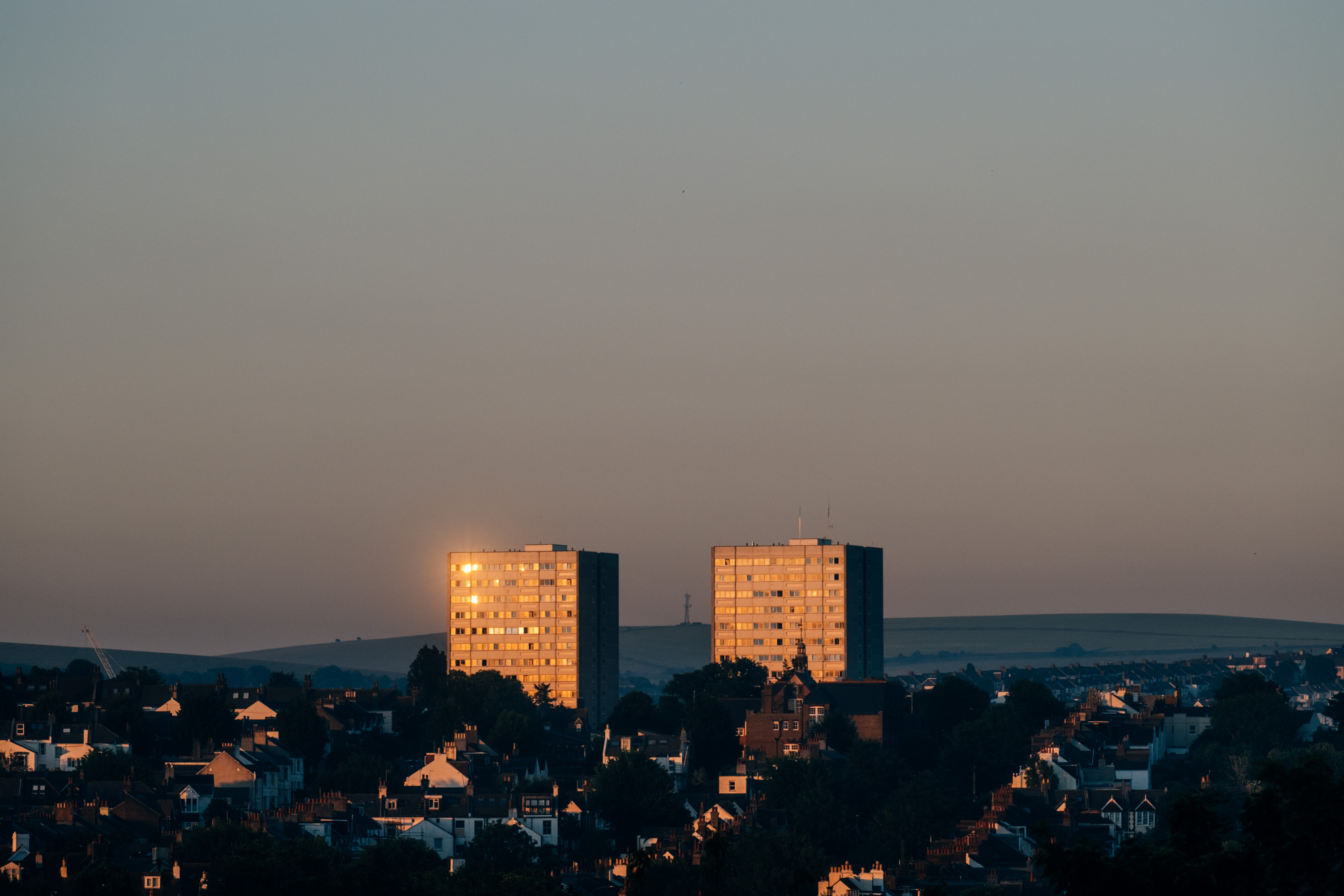 Two tower blocks in the distance at sunset with the sun’s light reflecting golden off the windows of the apartments. Taken on the Fujifilm X-T4 by Ian Howorth.