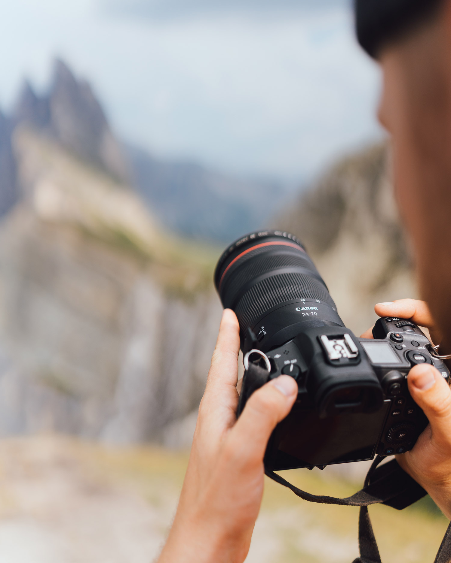 Jacob Murray tient l’appareil Canon R5 et l’objectif RF 24-70mm f/2.8 en main. Montagnes en arrière-plan.