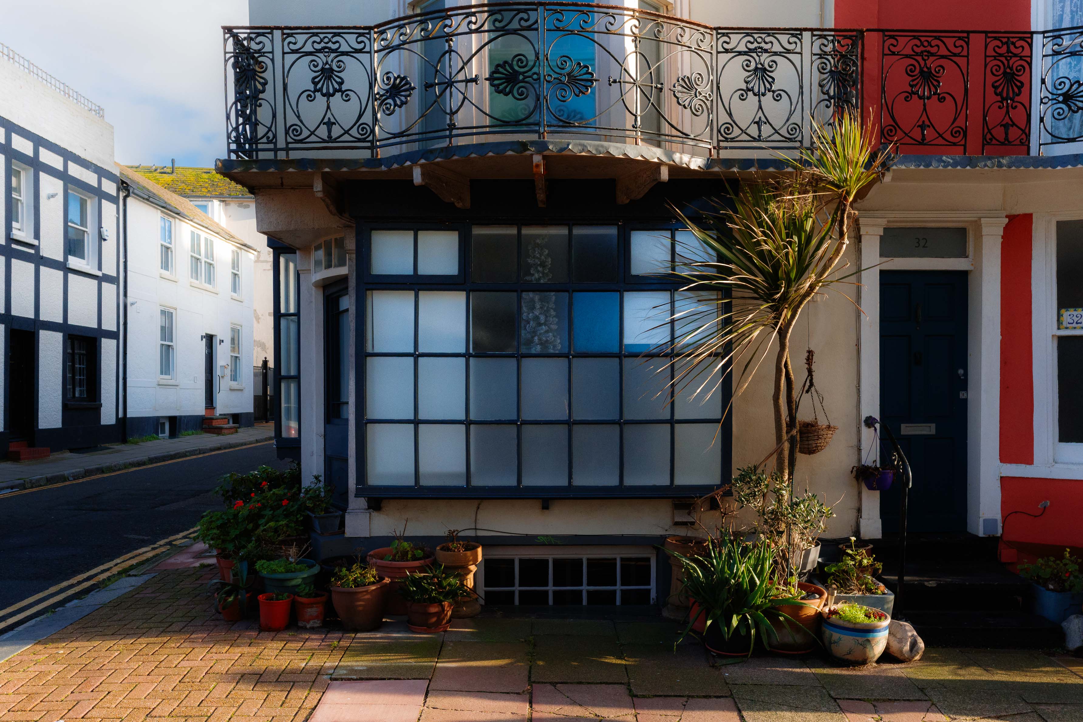 Streetaufnahme eines Eckgebäudes mit kunstvollen Balkongeländern, mattierten Fenstern und Topfpflanzen bei weichem natürlichem Tageslicht. Aufgenommen mit einer Ricoh GR IV.