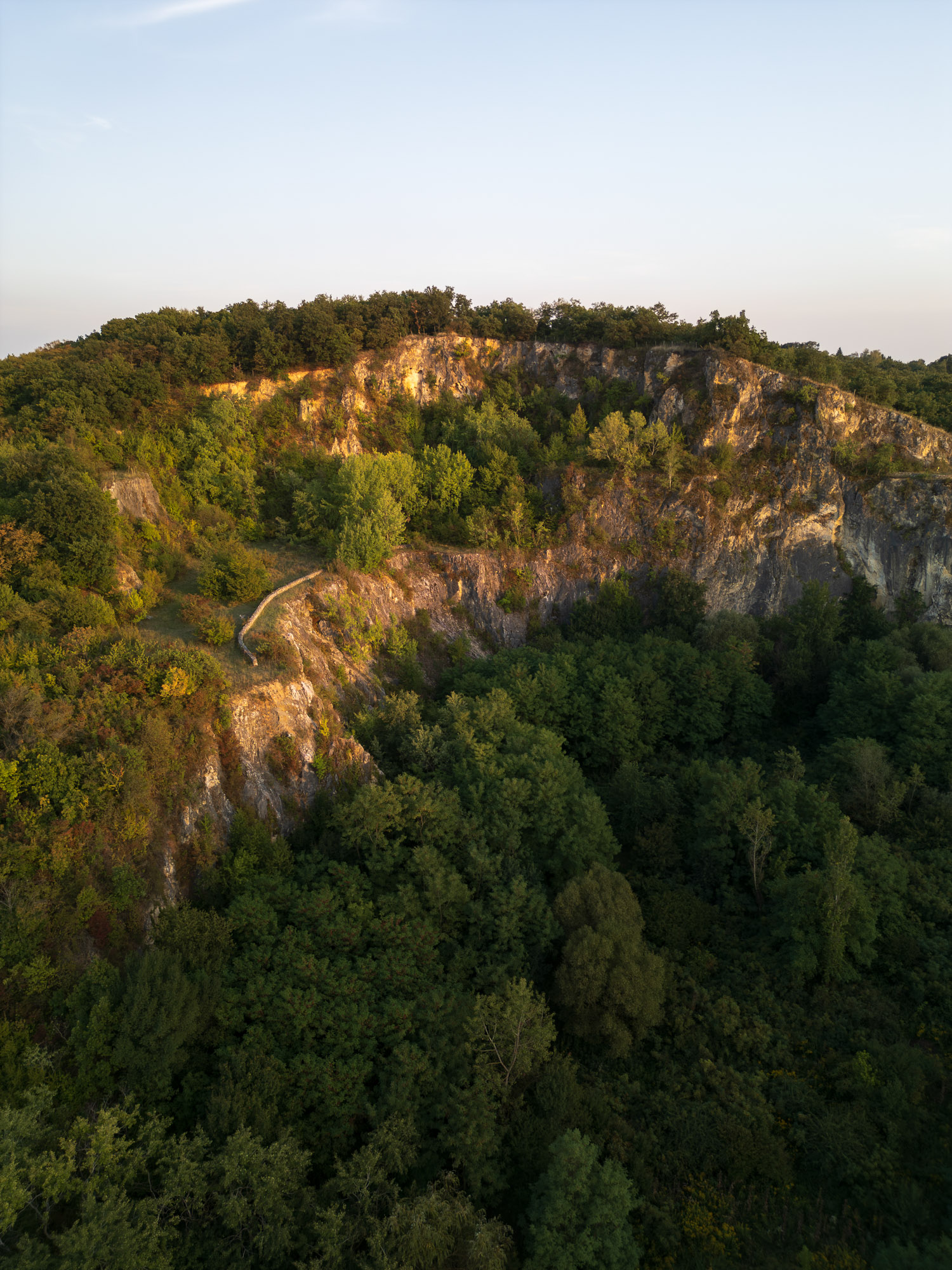 Drohnenaufnahme einer bewaldeten Felslandschaft im warmen Abendlicht. Aufgenommen von Adam Makkai mit einer DJI Mini 3 Pro.