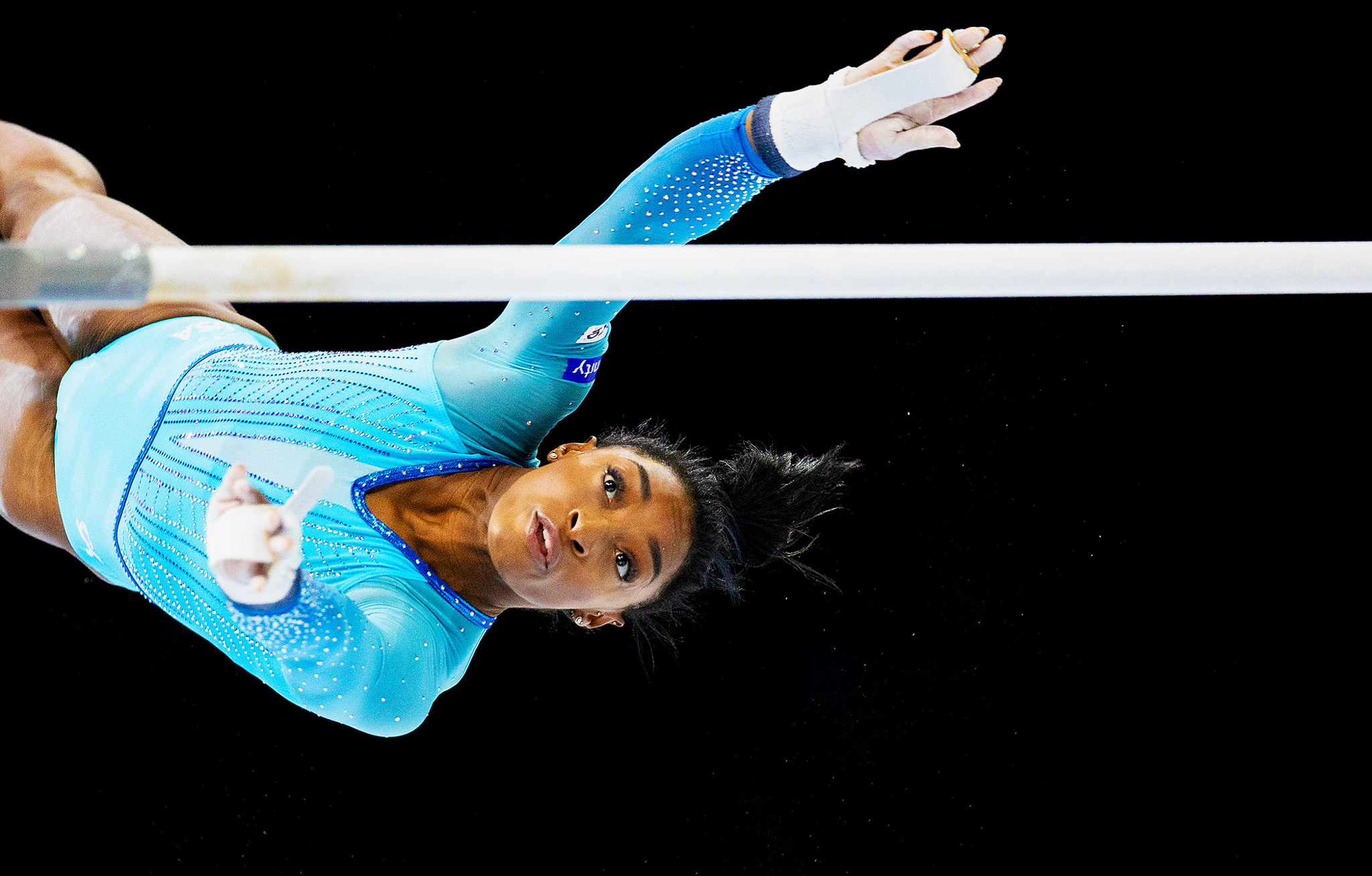 An action shot of Simone Biles mid-jump with the pole vault in front of her. By Iris van den Broek.