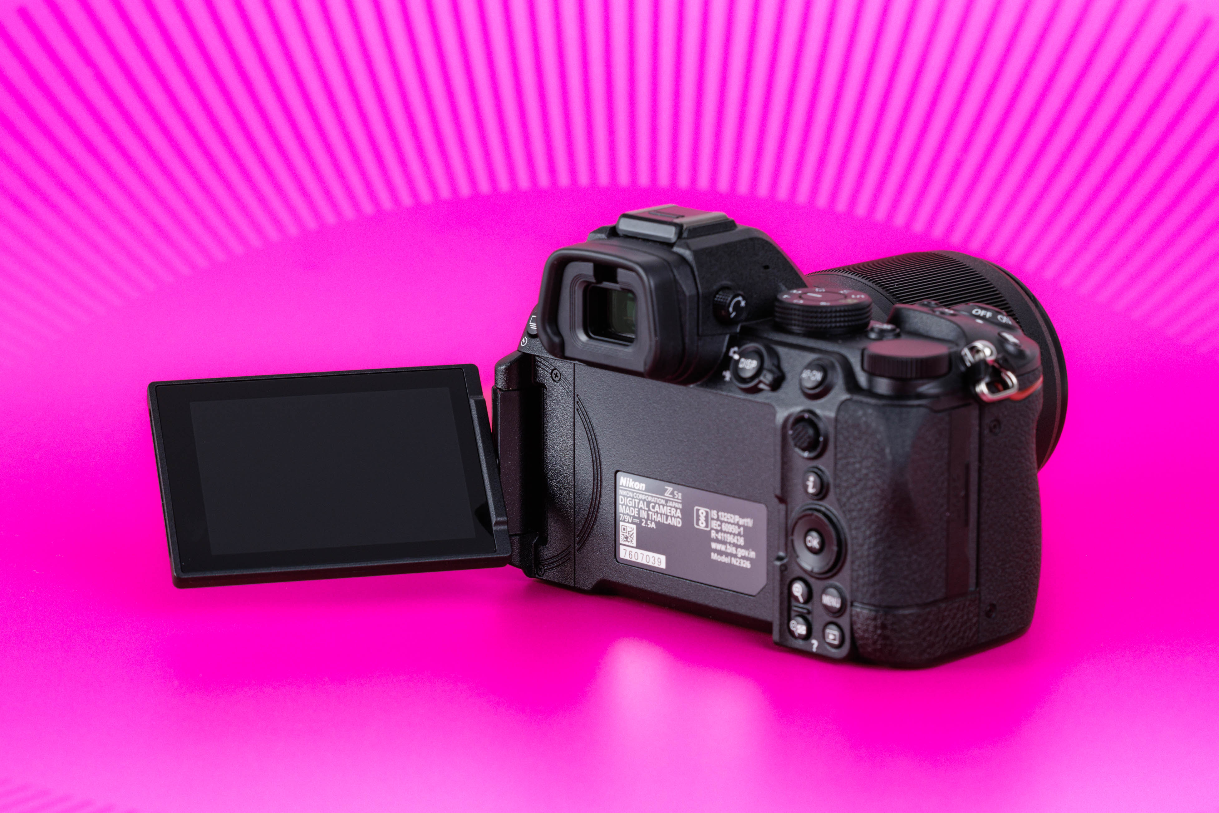 Studioaufnahme der Rückseite einer gebrauchten Nikon Z5 II mit ausgeklapptem Display vor leuchtend pinkem Hintergrund