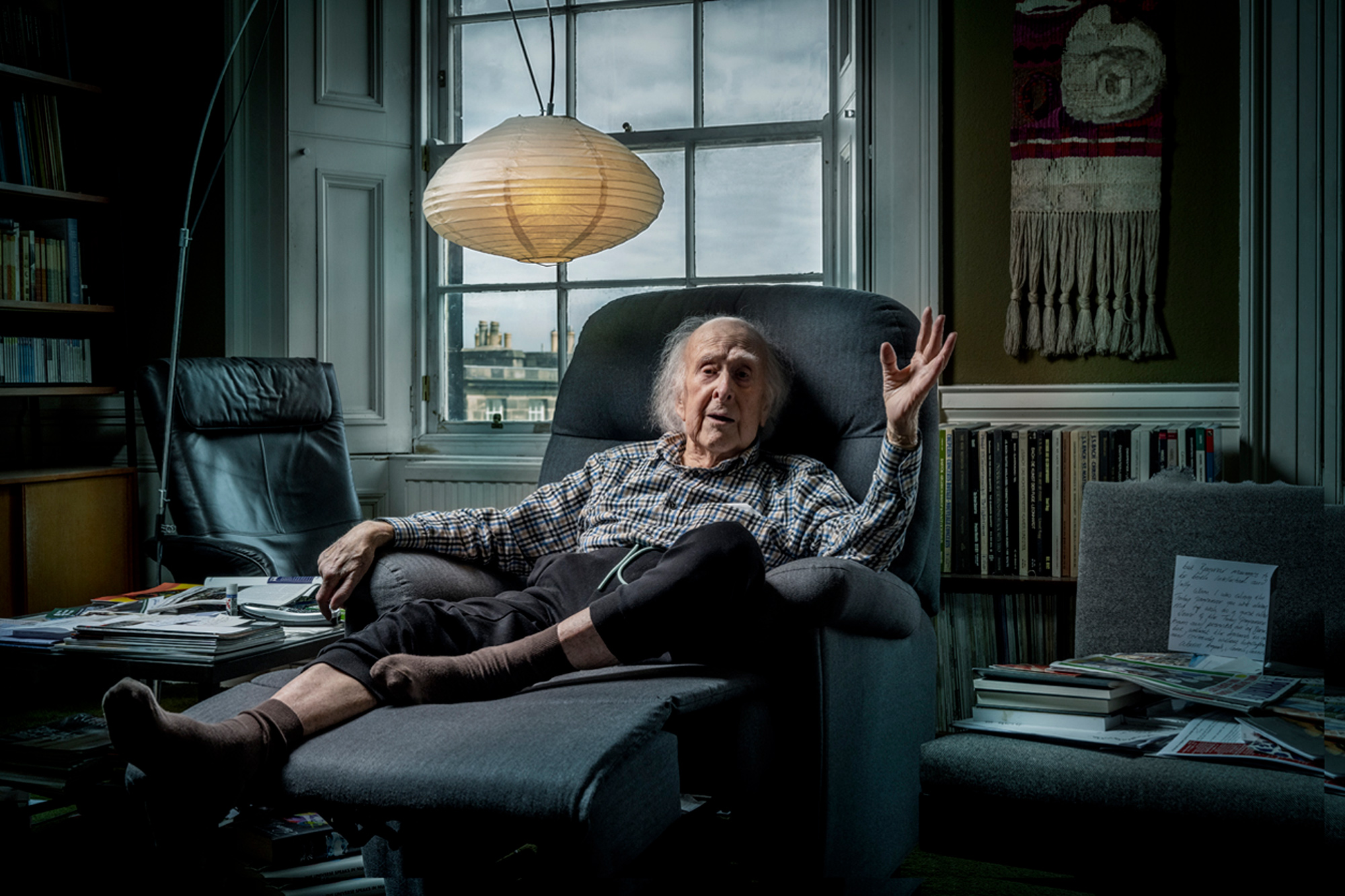 Portrait of Professor Higgs, sitting in an armchair in his office