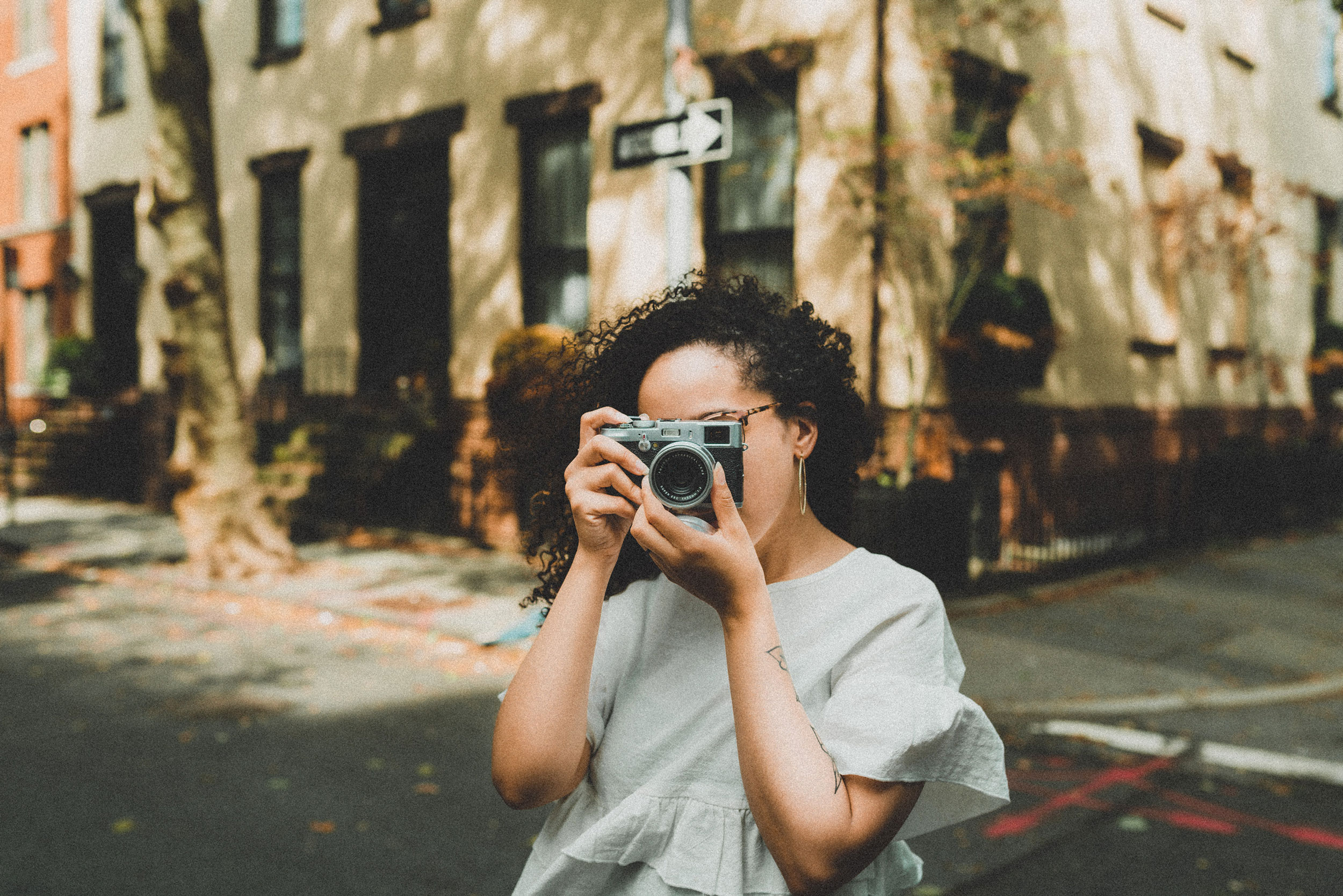 A student wearing a grey top taking a photo with a camera 