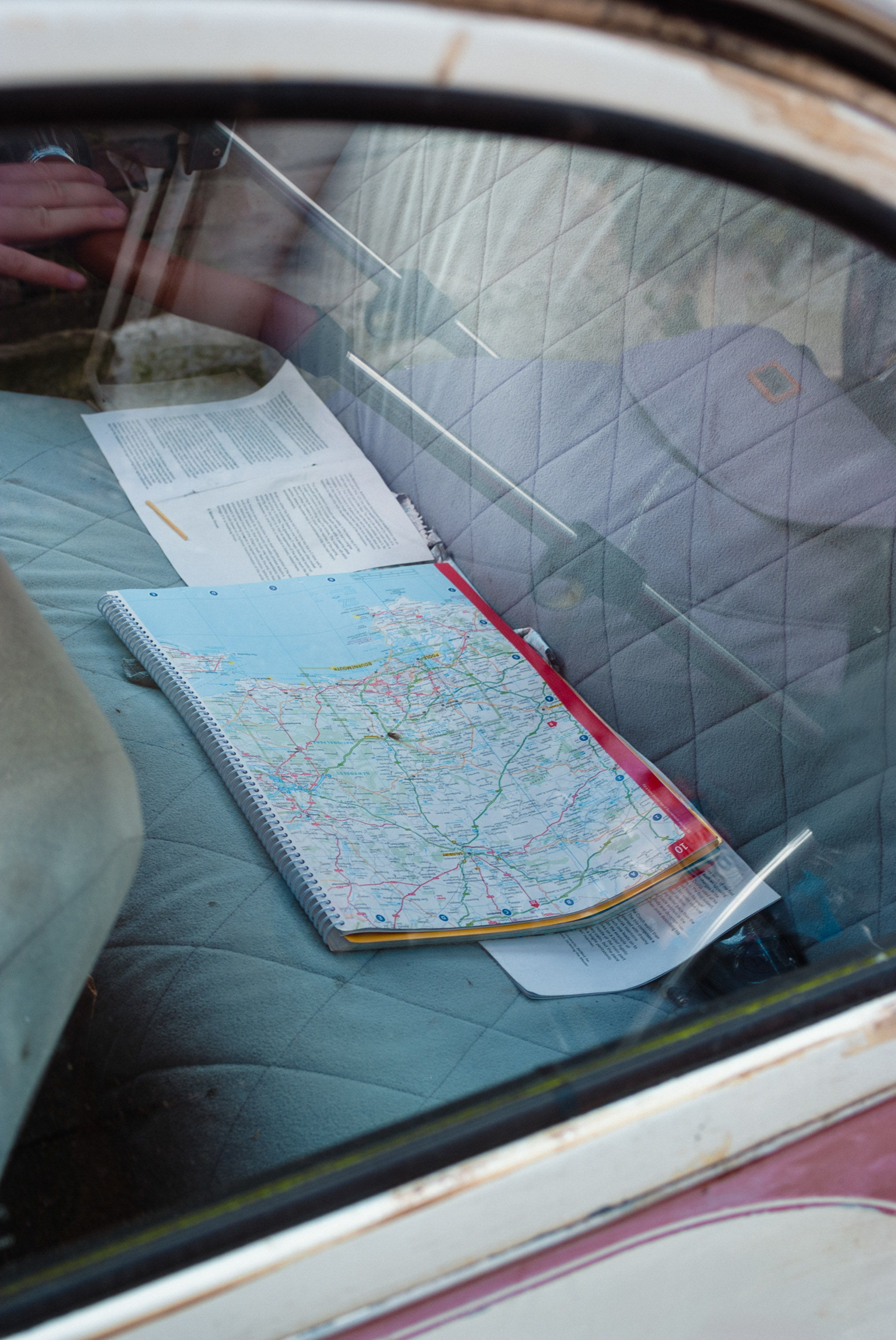 A map on the backseat of a vintage car through a window