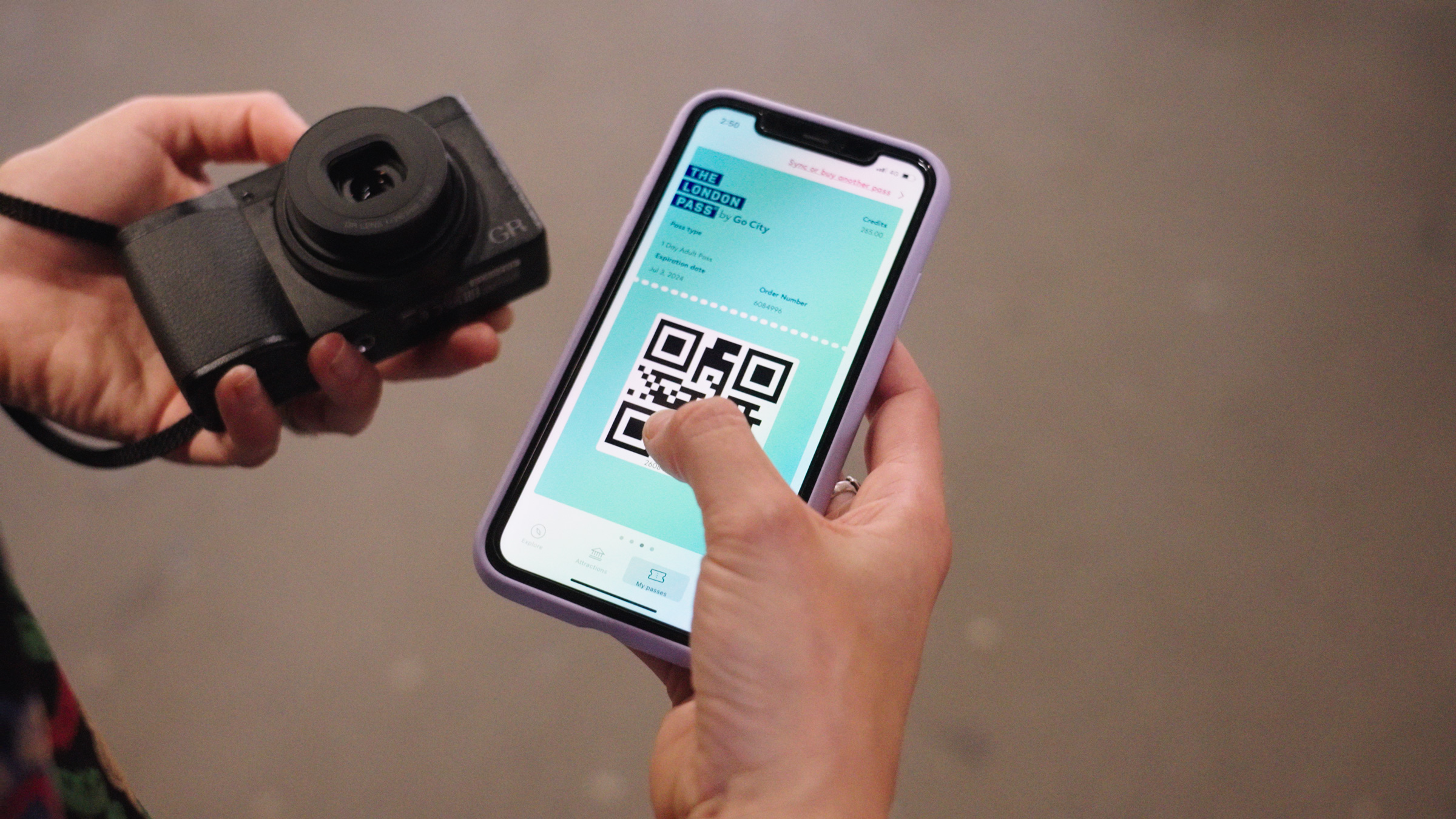 Une personne tenant le Ricoh GR III et un smartphone affichant le pass GoCity