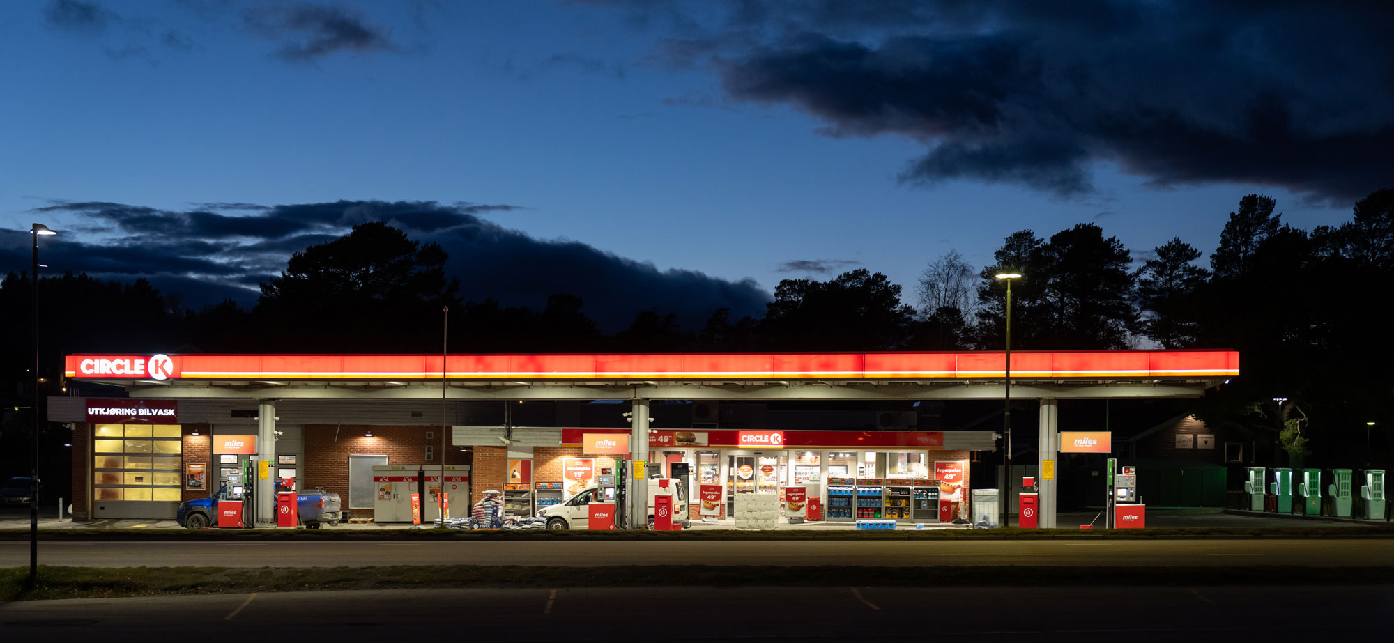 A petrol station at dusk, with parting clouds showing the navy sky.