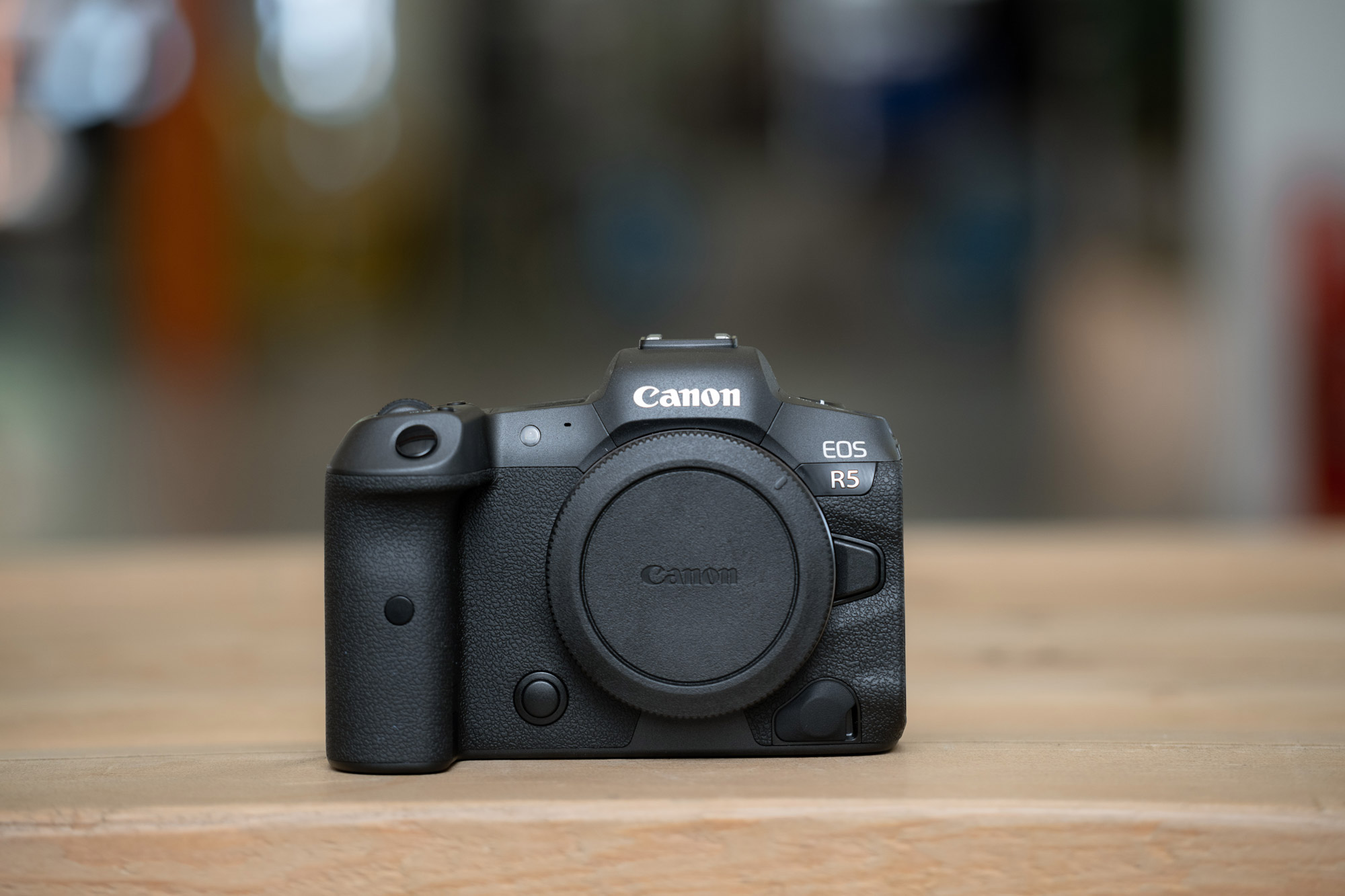 A front-on photo of a Canon EOS R5 sitting on a wooden table