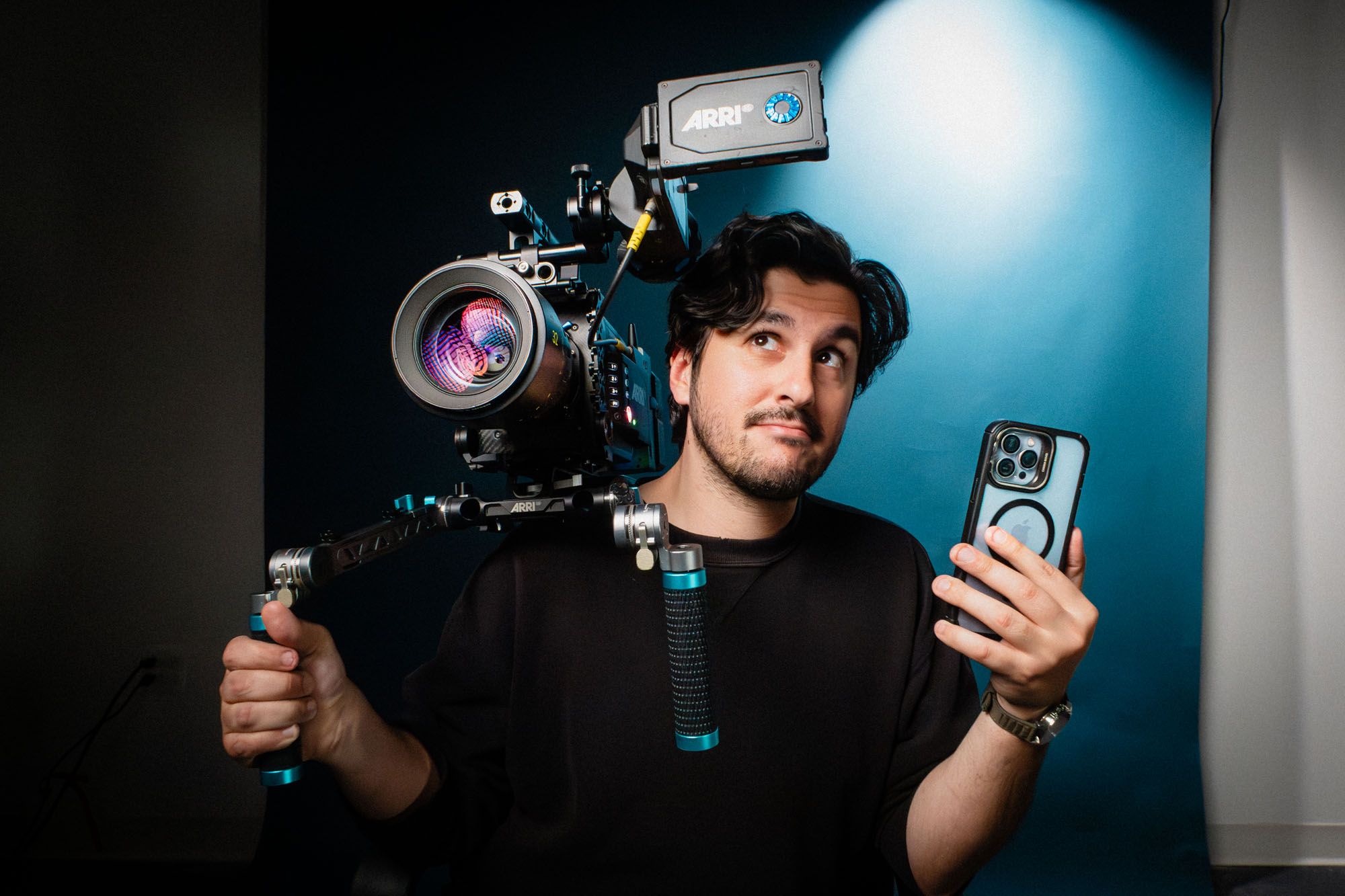 À gauche : une personne pose pour un test en haute sensibilité ISO tout en tenant une caméra de cinéma et un iPhone.