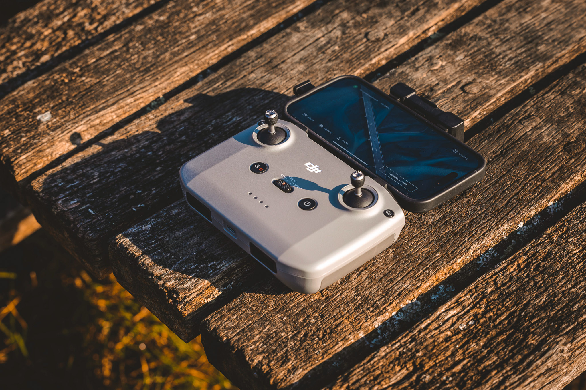 DJI RC‑N1 drone controller with smartphone placed on a wooden surface, showing the mobile-based flight control setup.