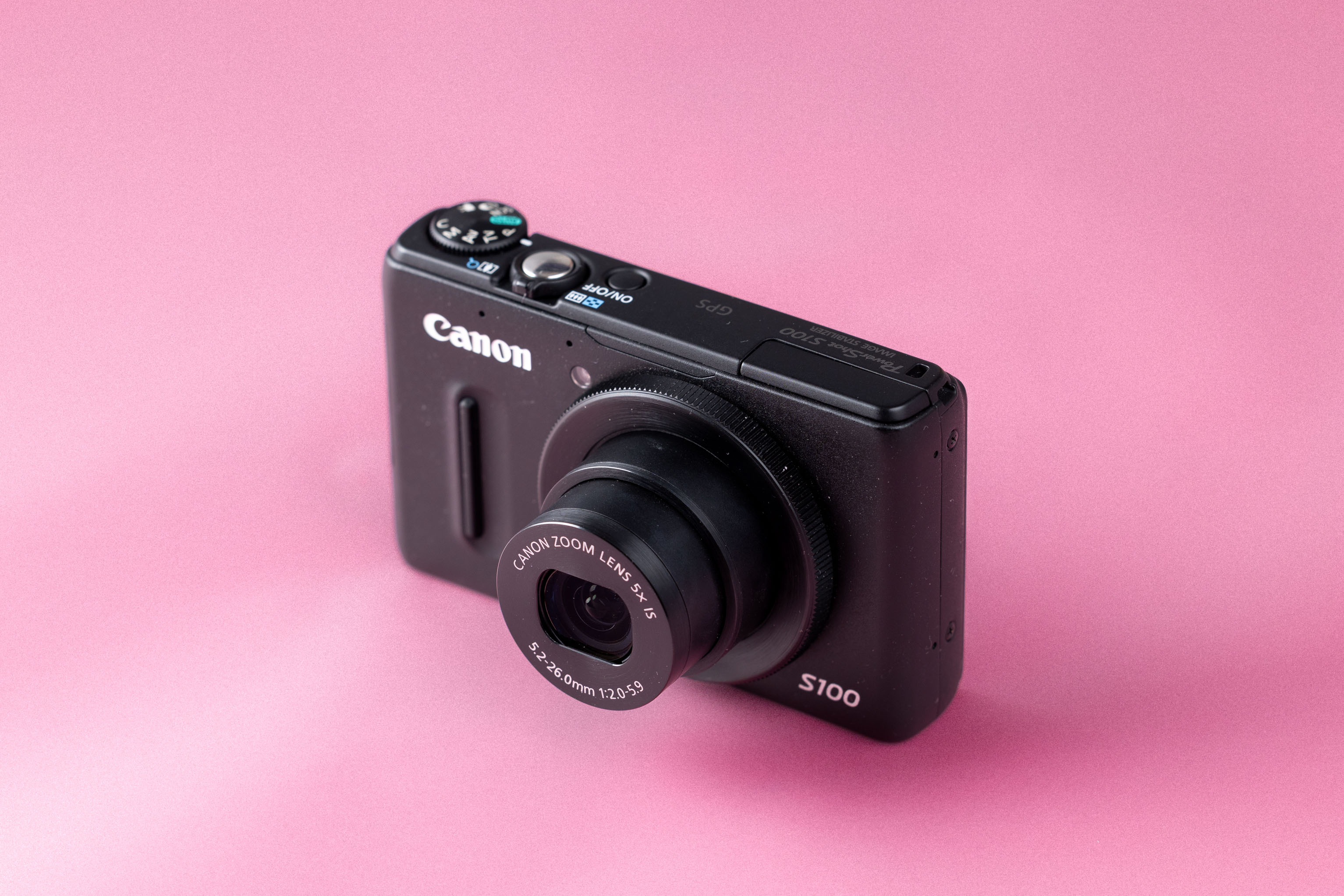 Canon Powershot S100 on a soft pink background.