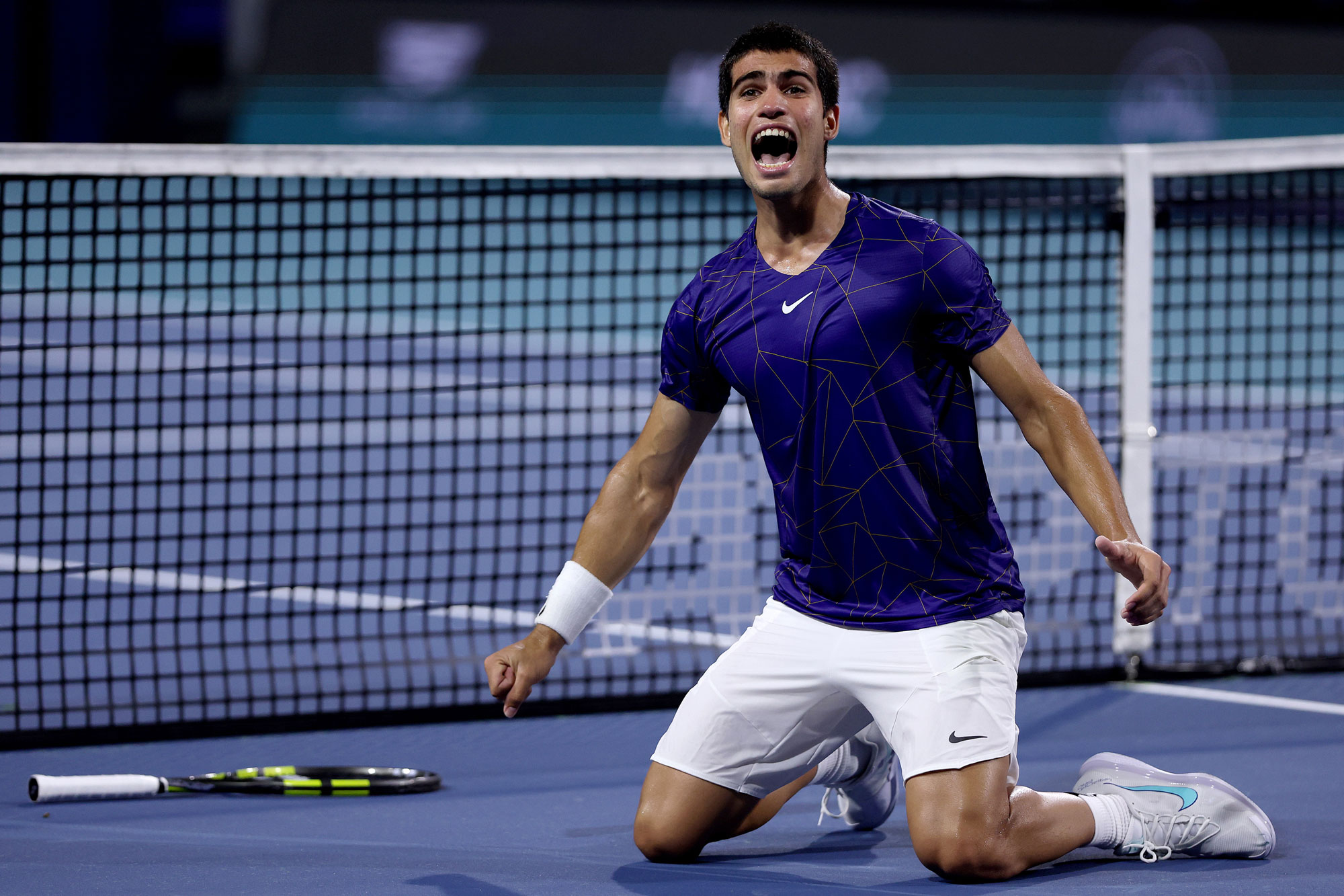 Carlos Alcaraz of Spain celebrates a match point against Miomir Kecmanovic of Serbia during the quarterfinals of the Miami Open at Hard Rock Stadium in Florida. His right hand is in a fist, having thrown his racquet on the floor behind him.