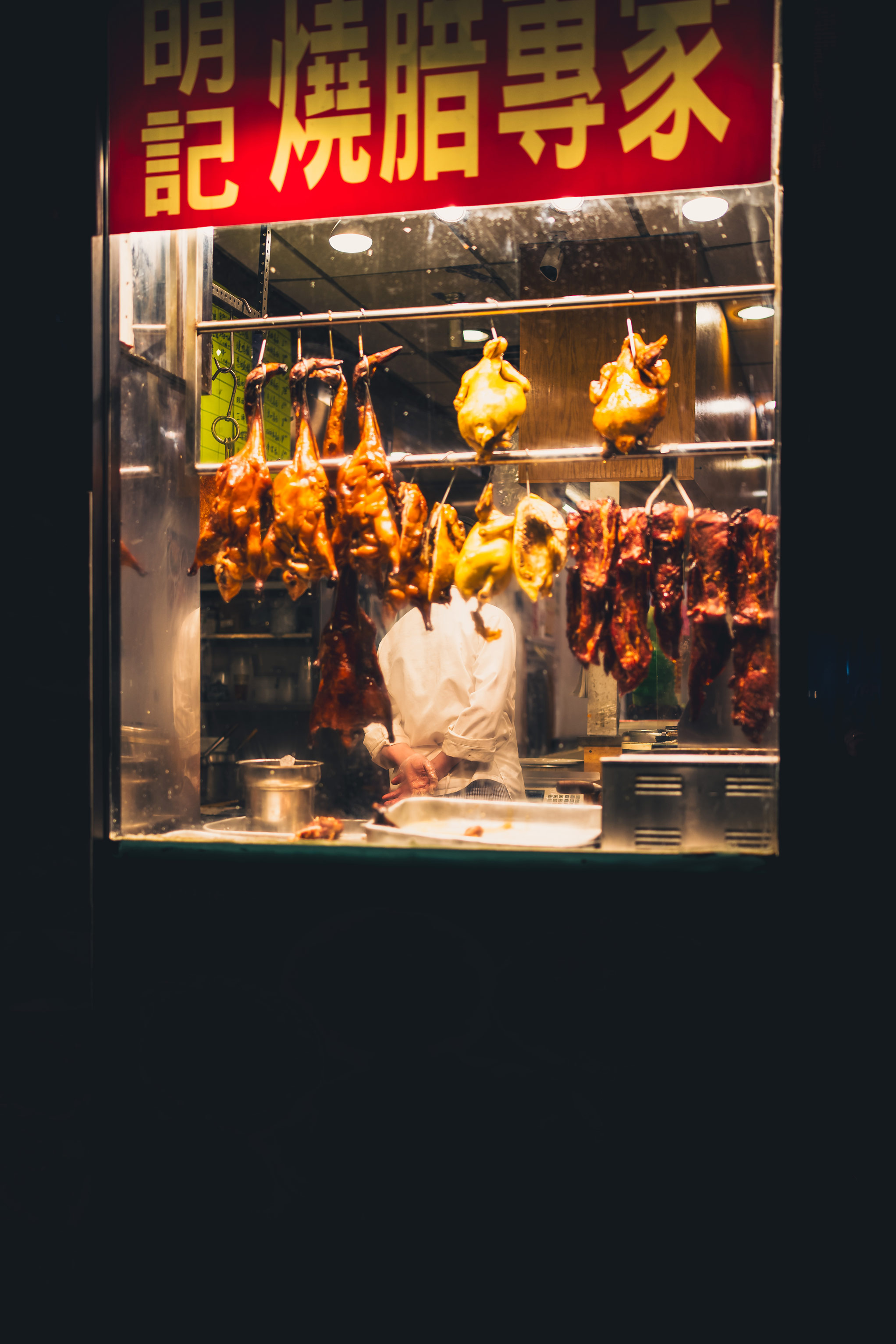 Restaurant window in New York City’s Chinatown at night with chef preparing chicken, photo by Manuel Pena on a Sony A7 III.