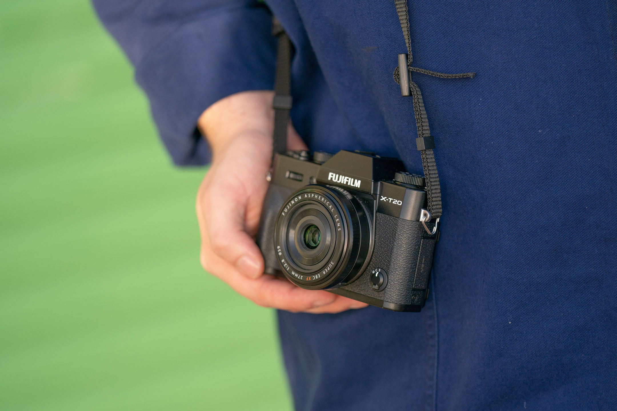 Hands holding a used Fujifilm X-T20 against a green background