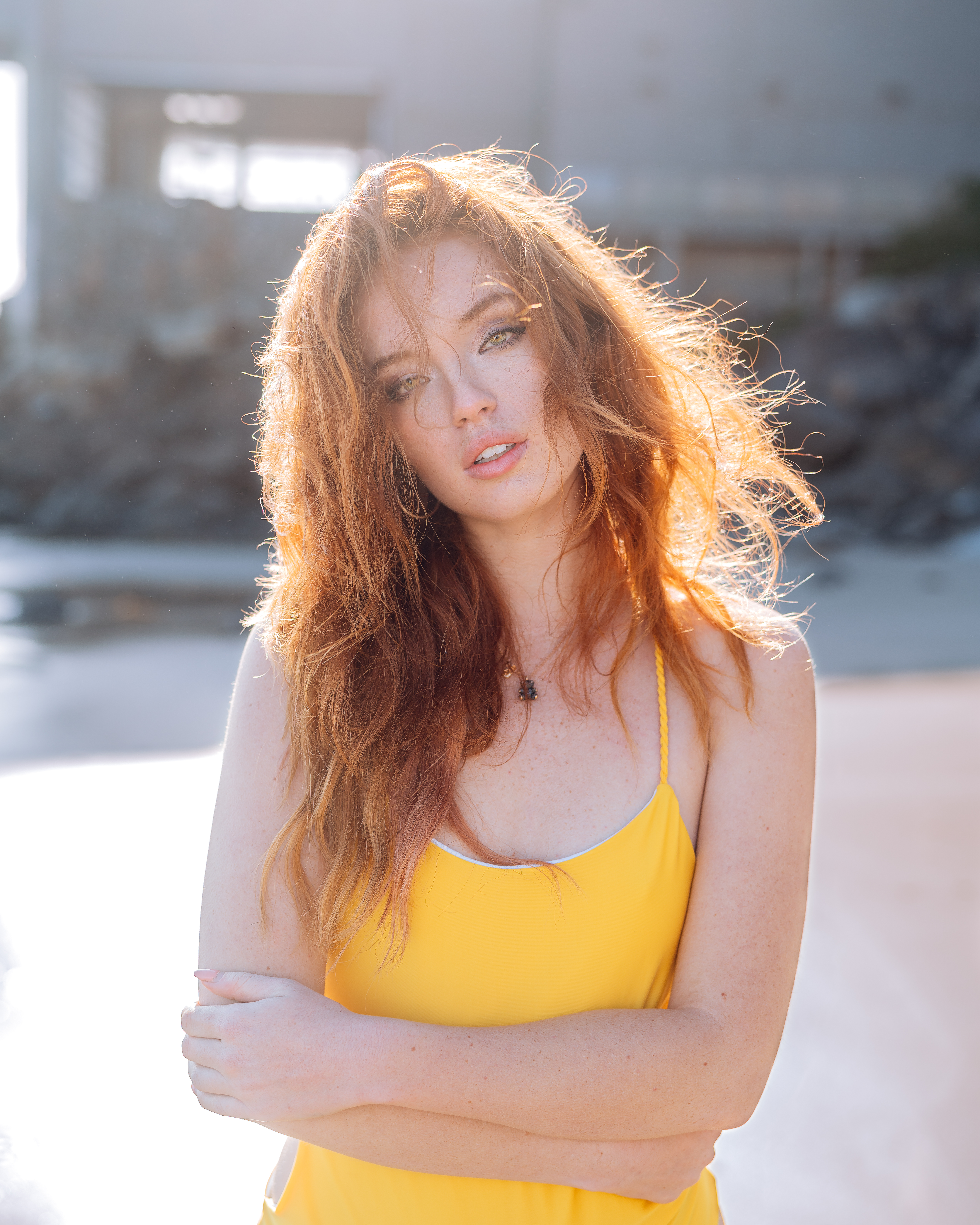 Red-haired woman model poses on a beach in the daylight.

