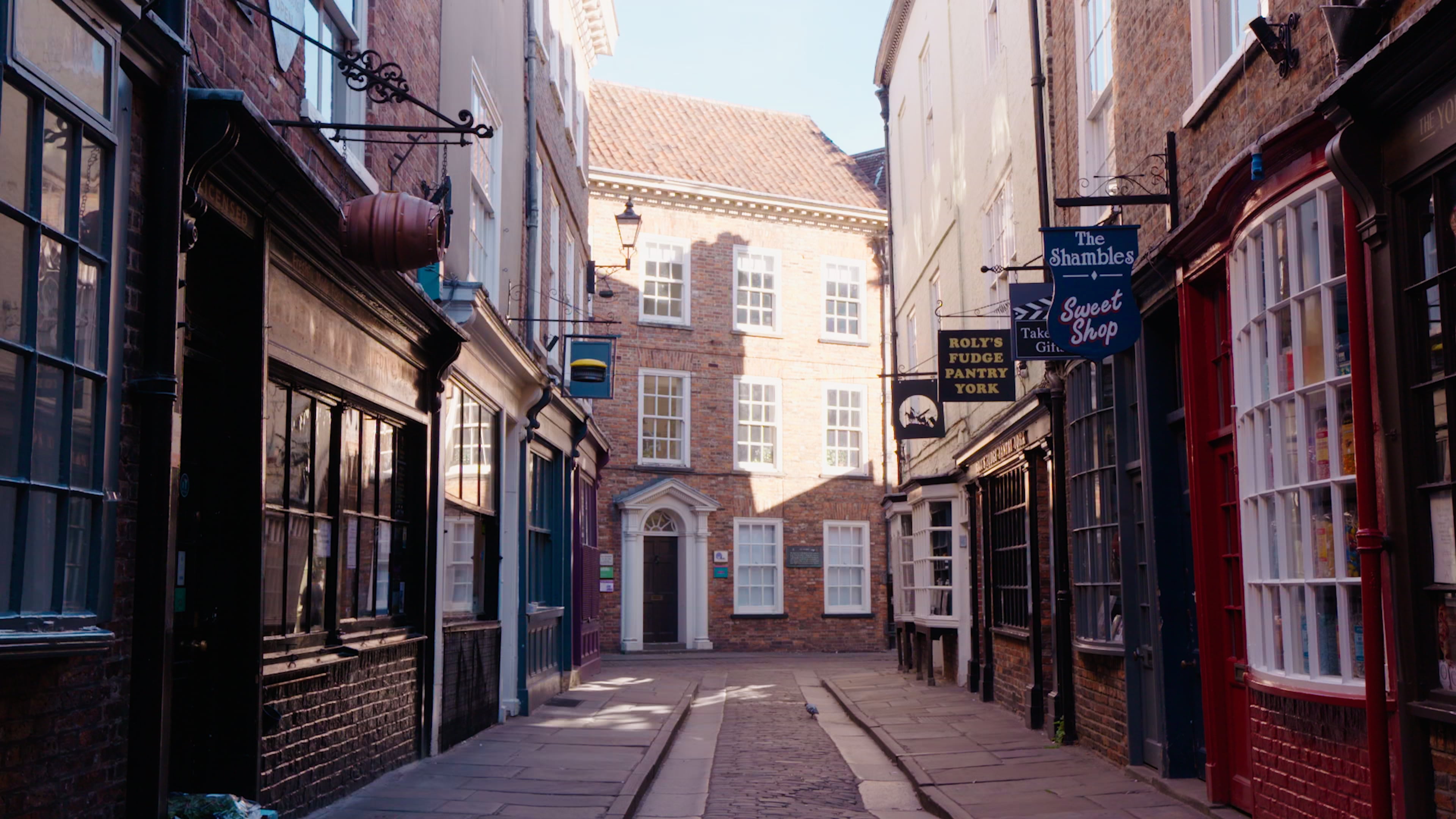 Scène de rue traditionnelle de York avec des petites boutiques de chaque côté de la rue et une maison en briques au bout de la rue.