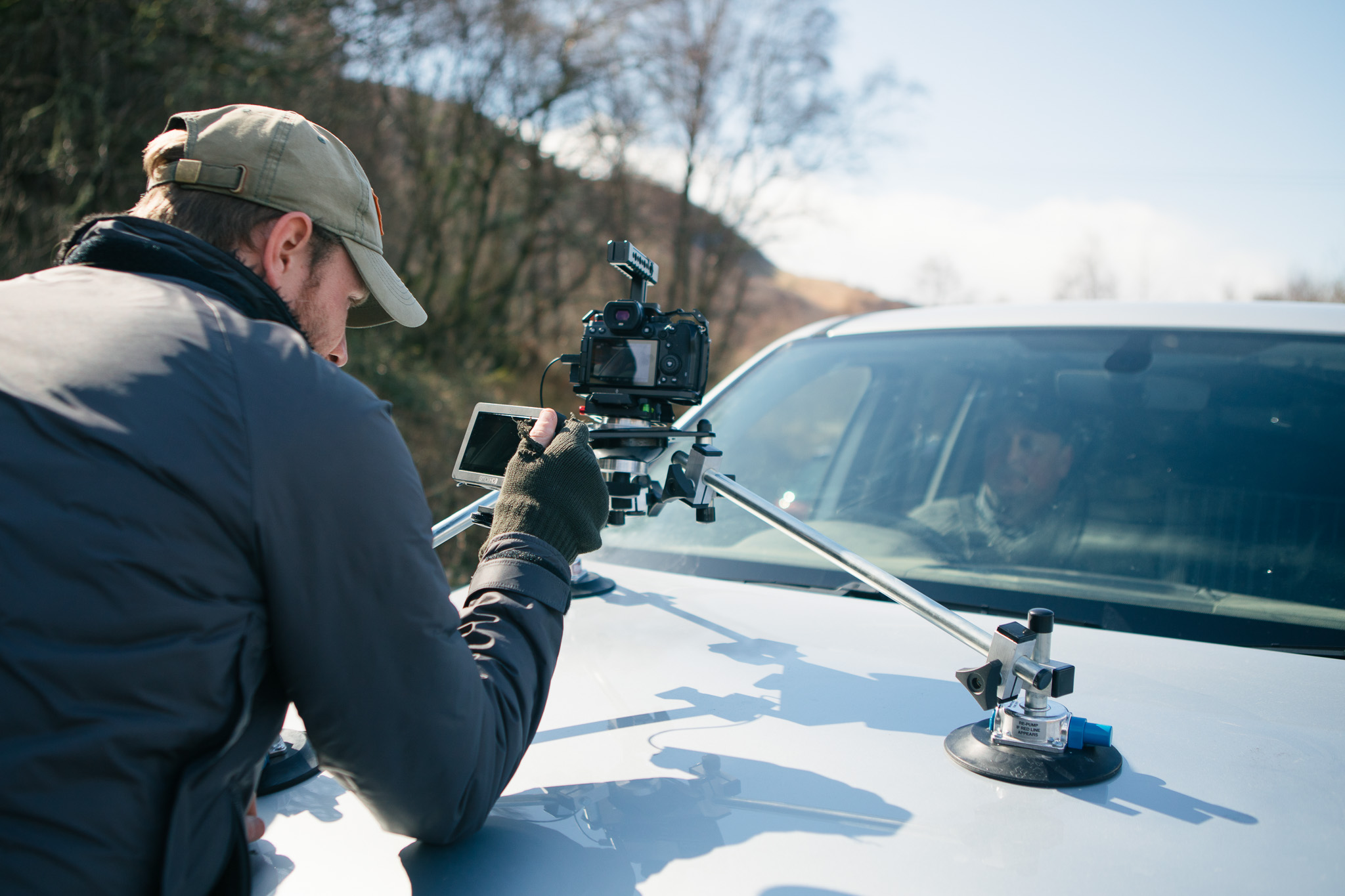 A person setting up a camera to be mounted onto a car bonnet