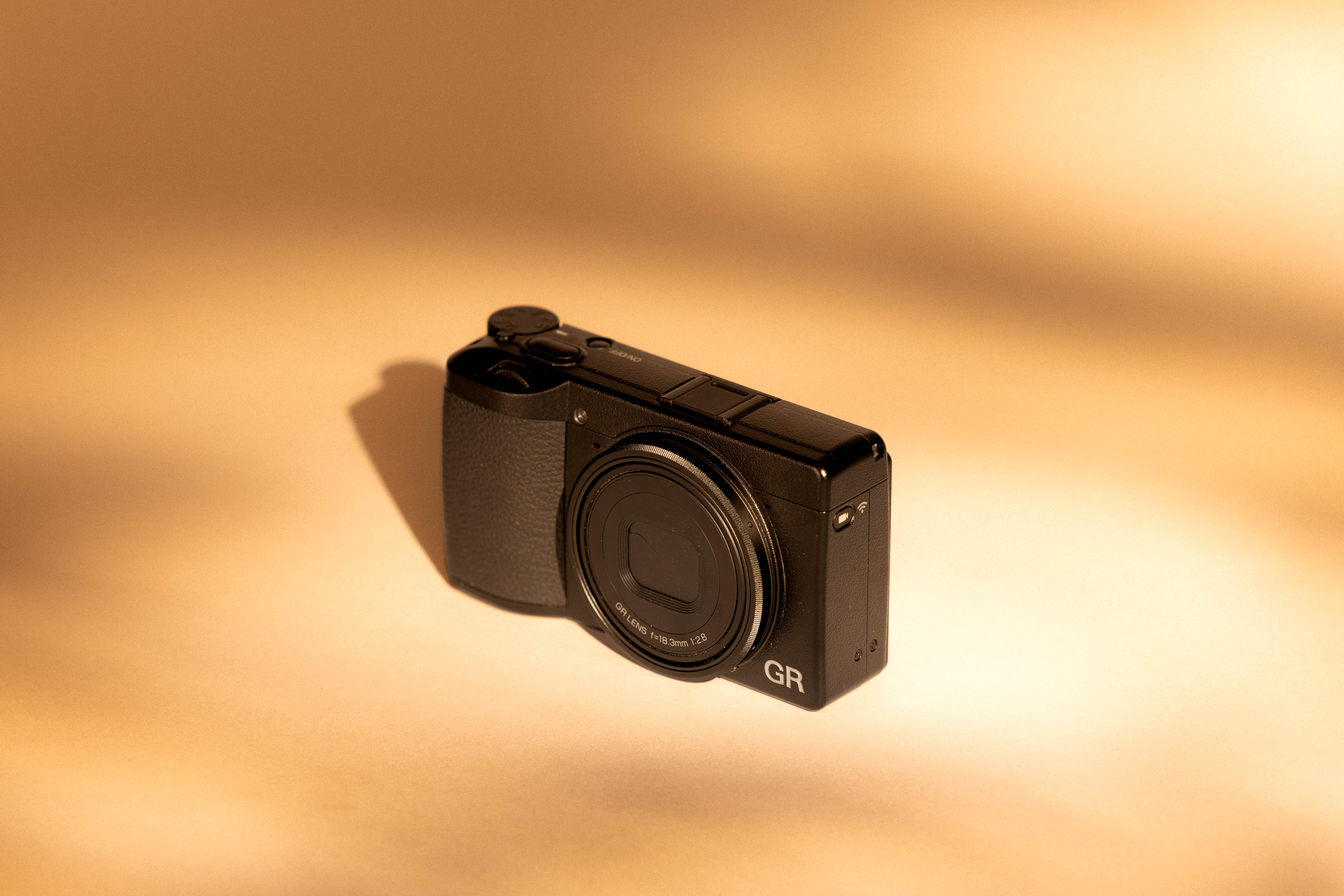 Ricoh GR III auf cremefarbenem Hintergrund