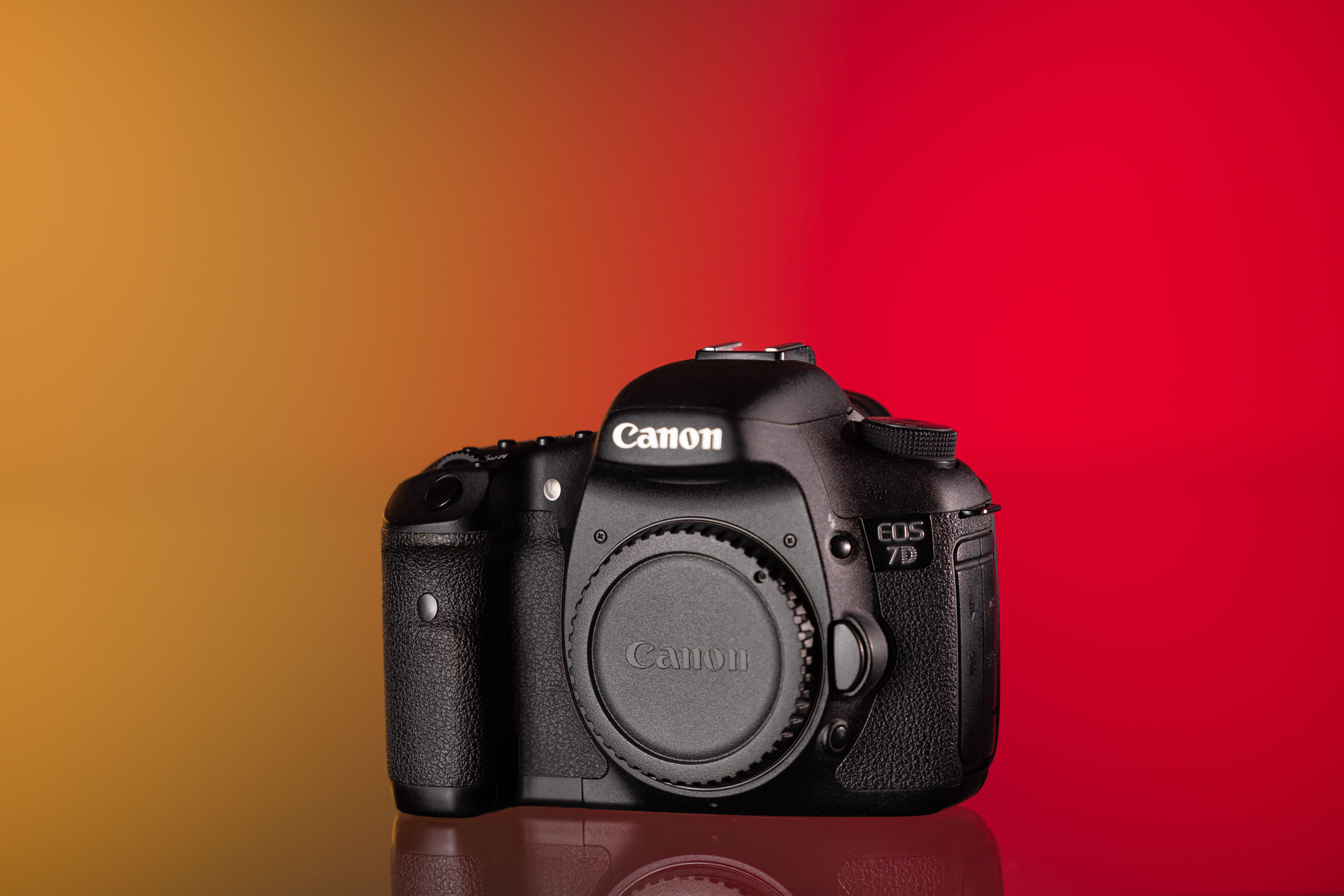 Cámara Canon EOS 7D usada sobre fondo amarillo y rojo