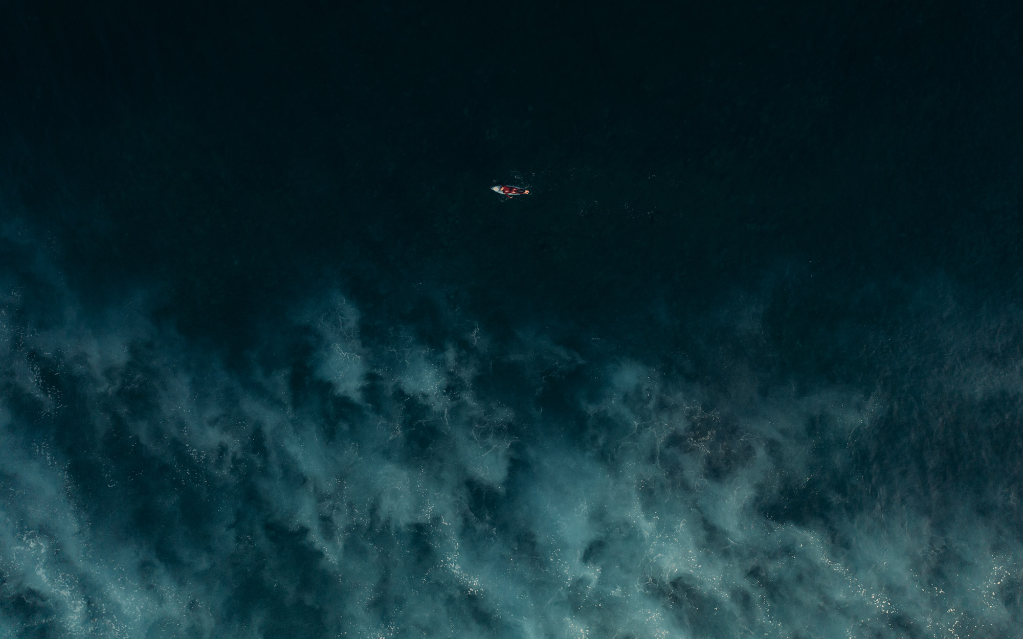 A bird’s eye view of a kayak floating on a dark sea, created with a DJI Mavic 2 Pro by travel photographer Harry Pope.