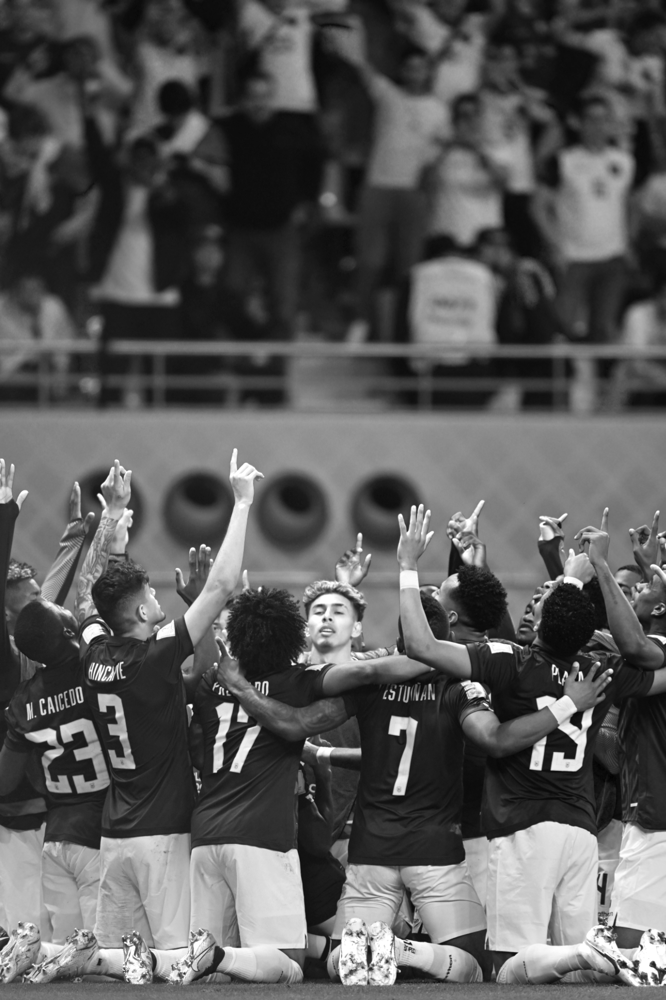 Une photo en noir et blanc de l'équipe d'Équateur à genoux en cercle, les mains tendues vers le ciel juste avant le match contre les Pays Bas, Coupe du Monde 2022. Photo prise avec un Nikon Z9 par Ryu Voelkel.