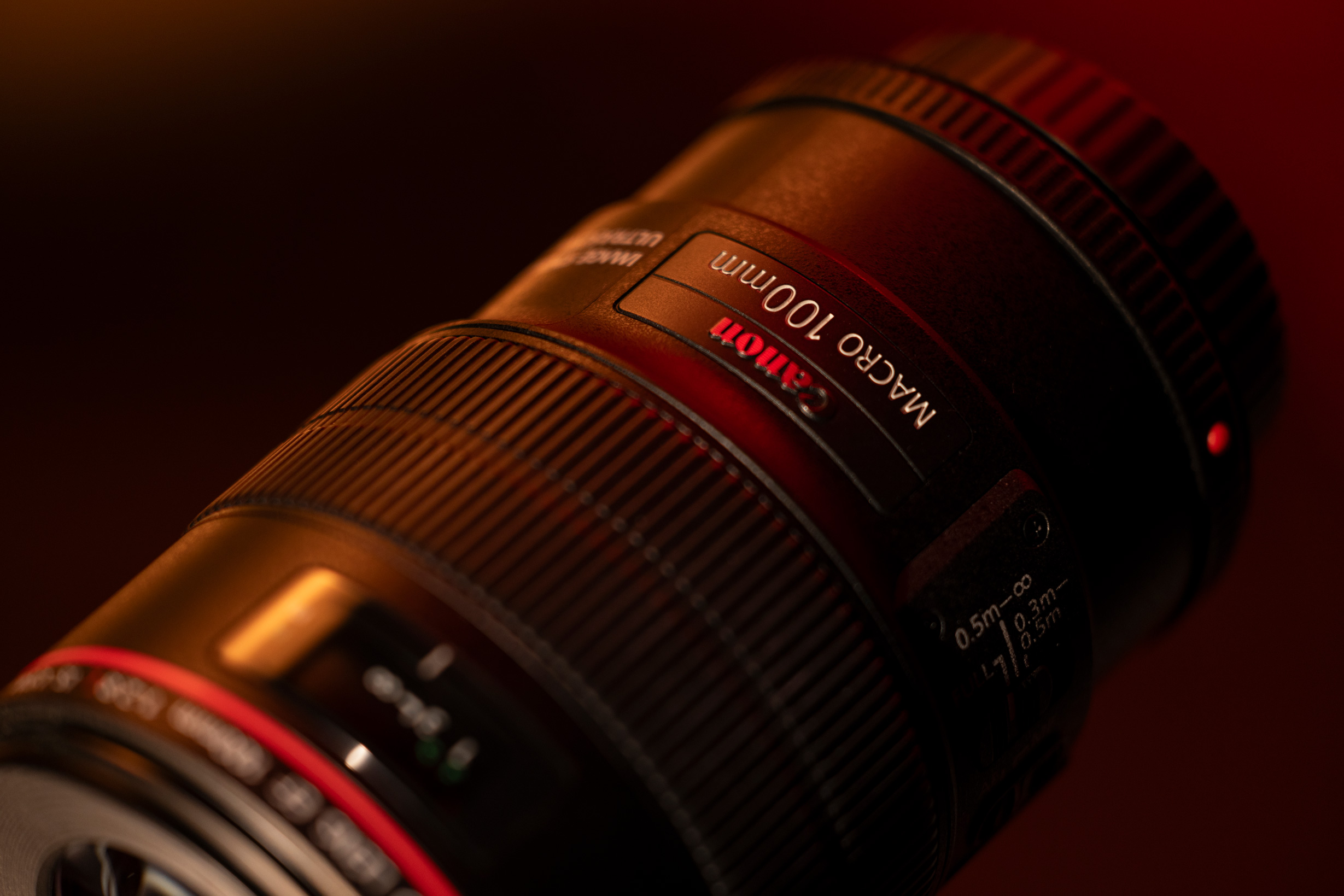 Canon EF 100mm f/2.8 L Macro IS USM on a red and black background.