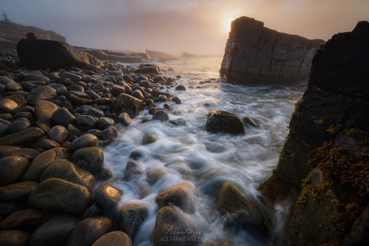 Waves roll over rocks by a cliff.