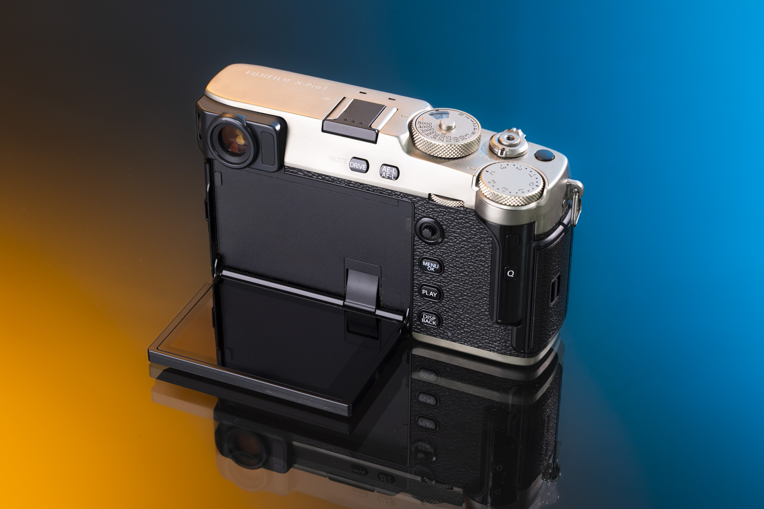 Arrière du Fujifilm X-Pro 3 Dura avec l'écran caché vers le bas sur un fond orange et bleu