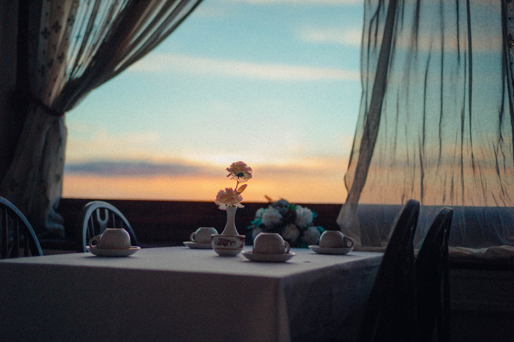Ein Tisch in einem Hotel mit umgedrehten Teetassen und einer Blume in einer Vase darauf 

