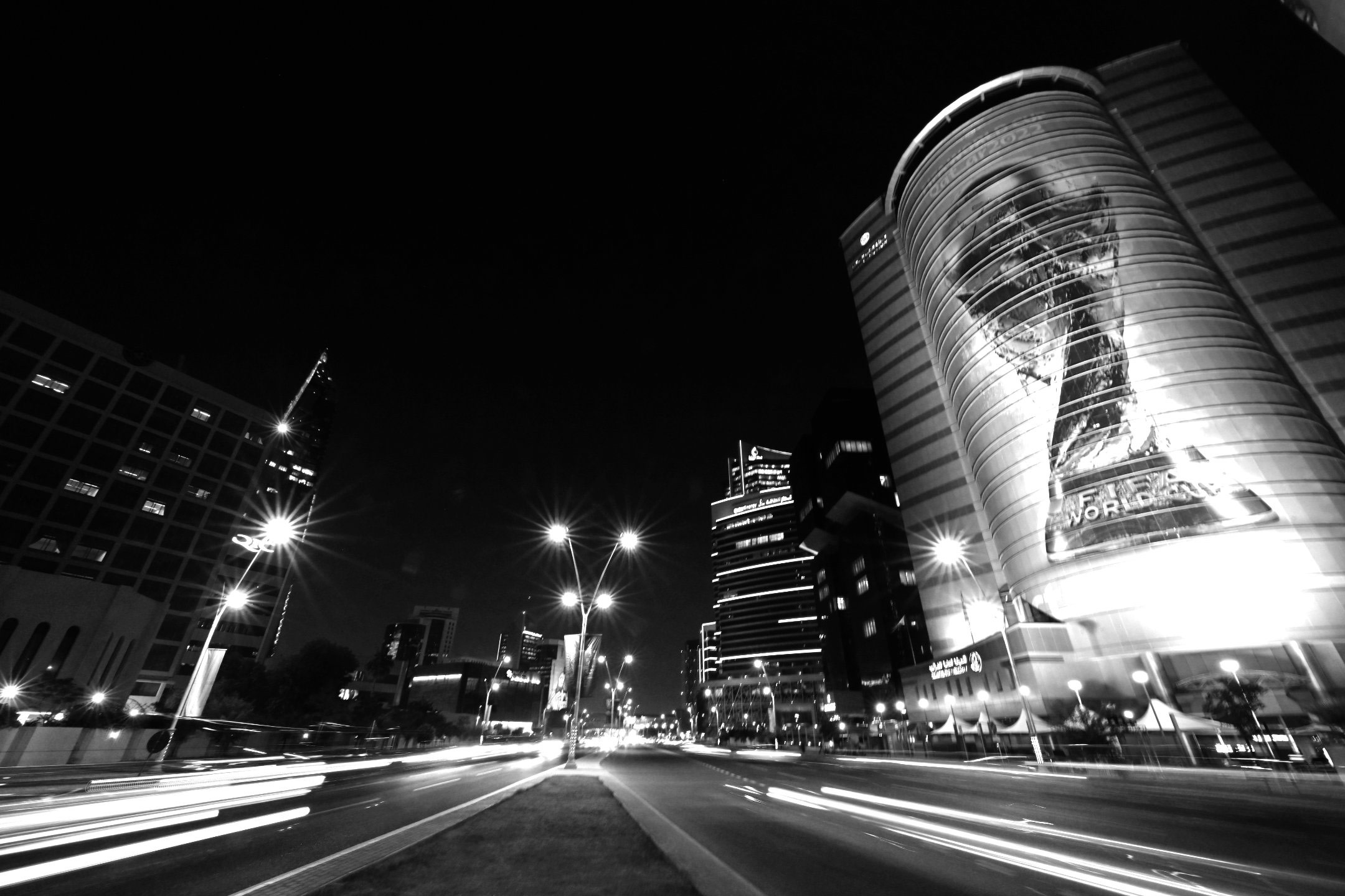 Eine Schwarz-Weiß-Langzeitbelichtung einer Straße in Doha, Katar, während der Fußballweltmeisterschaft 2022, mit Autoscheinwerfern, die Lichtspuren erzeugen, aufgenommen mit einer Nikon Z9 von Ryu Voelkel