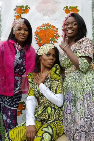 Trois femmes africaines de la Cité de la Joie portant des tenues confectionnées à partir de tissus wax Vlisco