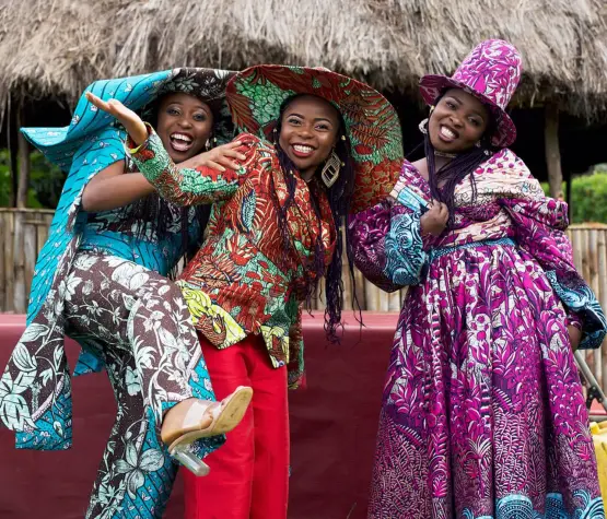 Trois femmes africaines de la Cité de la Joie portant des tenues confectionnées à partir de tissus wax Vlisco