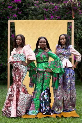 Trois femmes africaines de la Cité de la Joie portant des tenues confectionnées à partir de tissus wax Vlisco