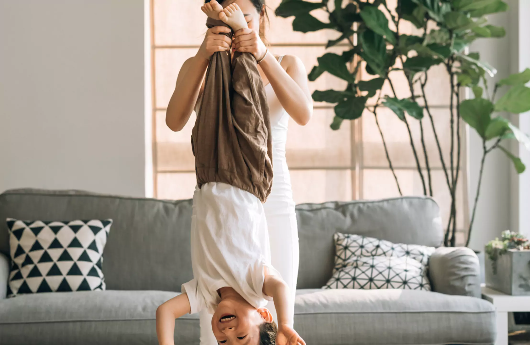 Woman playing with child, holding them upside down