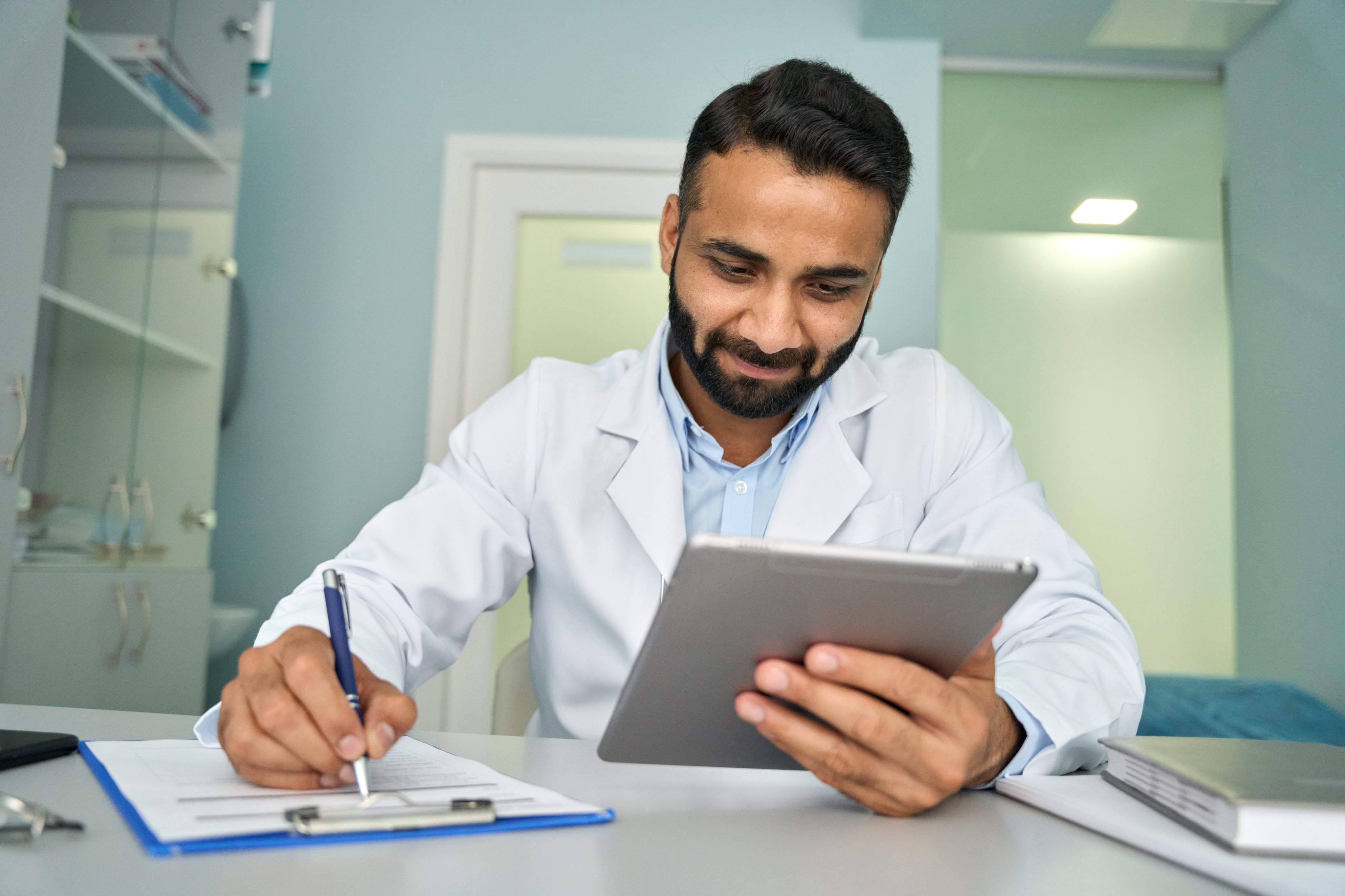 Man is using tablet and writing on paper