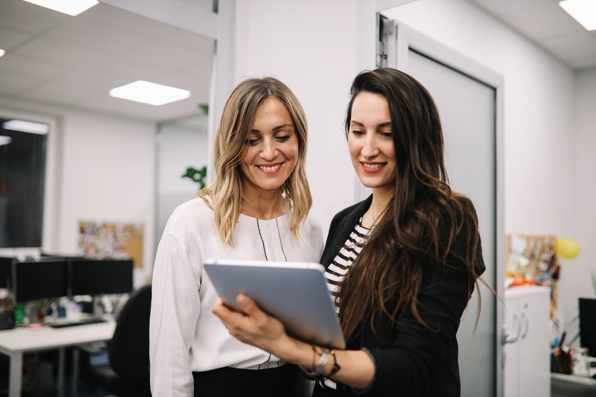 Two professionals discussing a tablet in a modern office setting