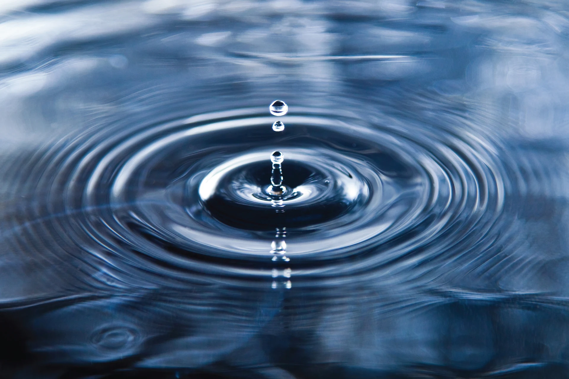 Water droplet creating ripples in a body of water, symbolizing transformation.