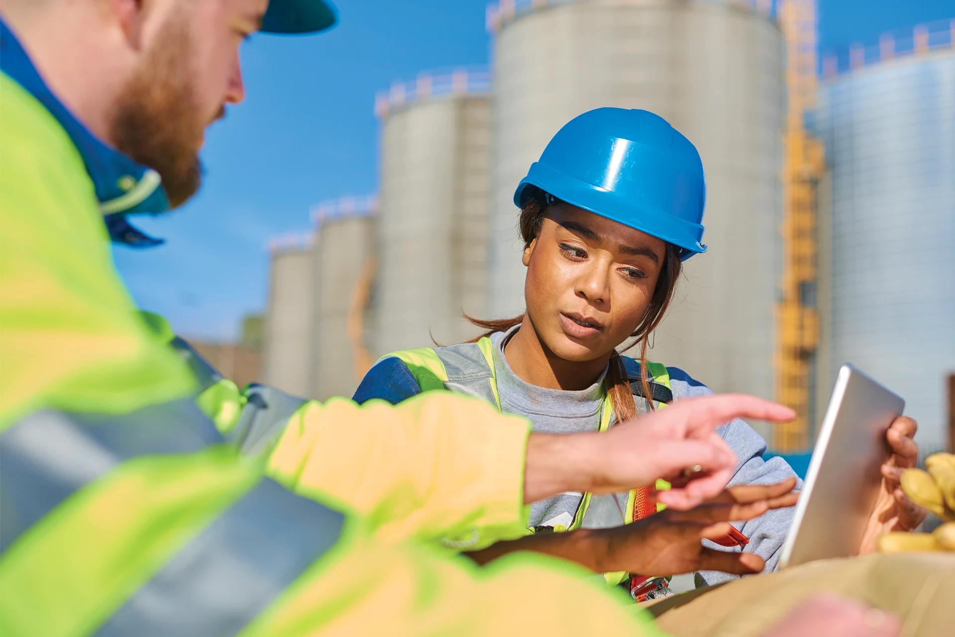 Two professionals discussing a tablet on a construction site.