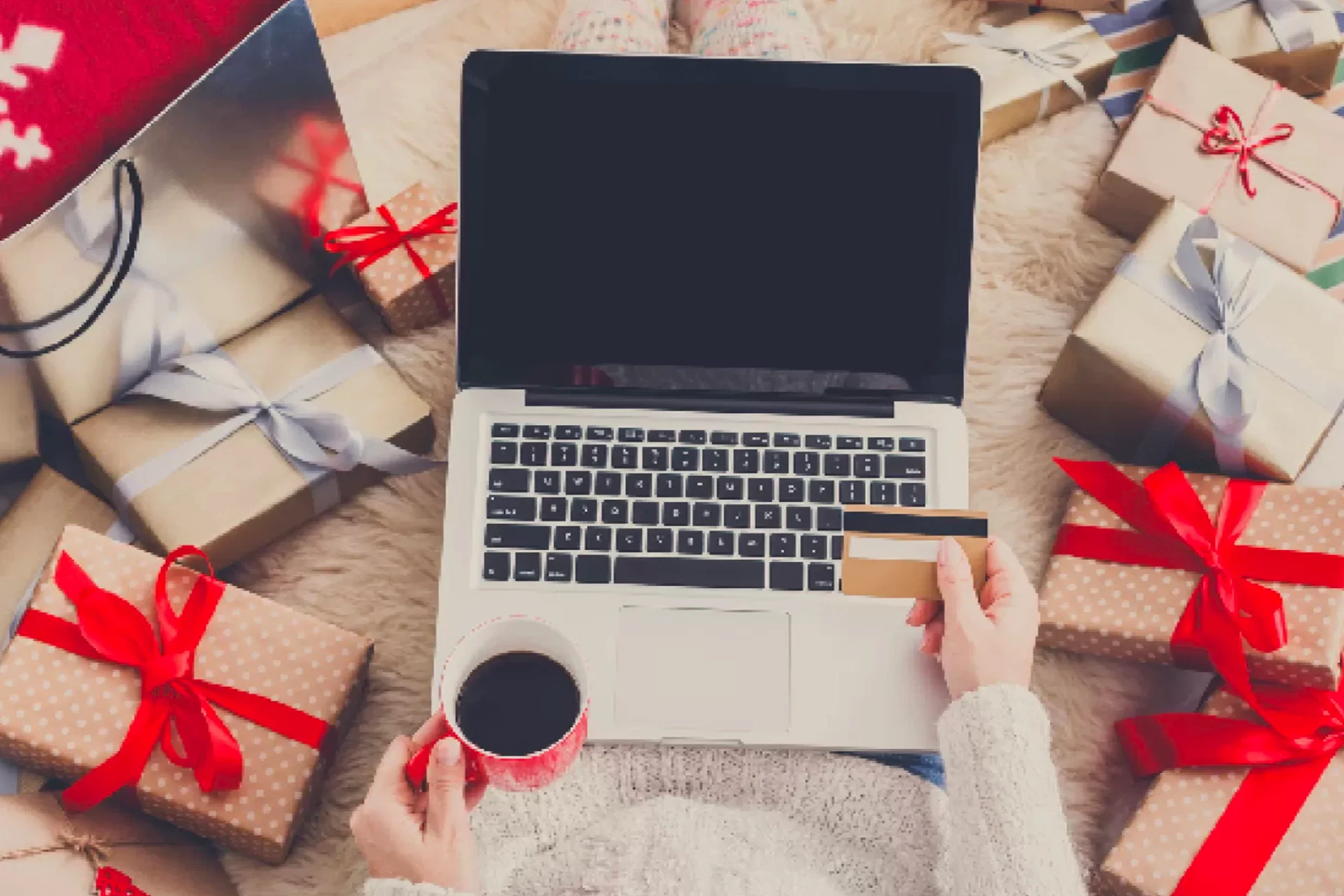 Shopping online with credit card laptop and coffee mug near Christmas gifts