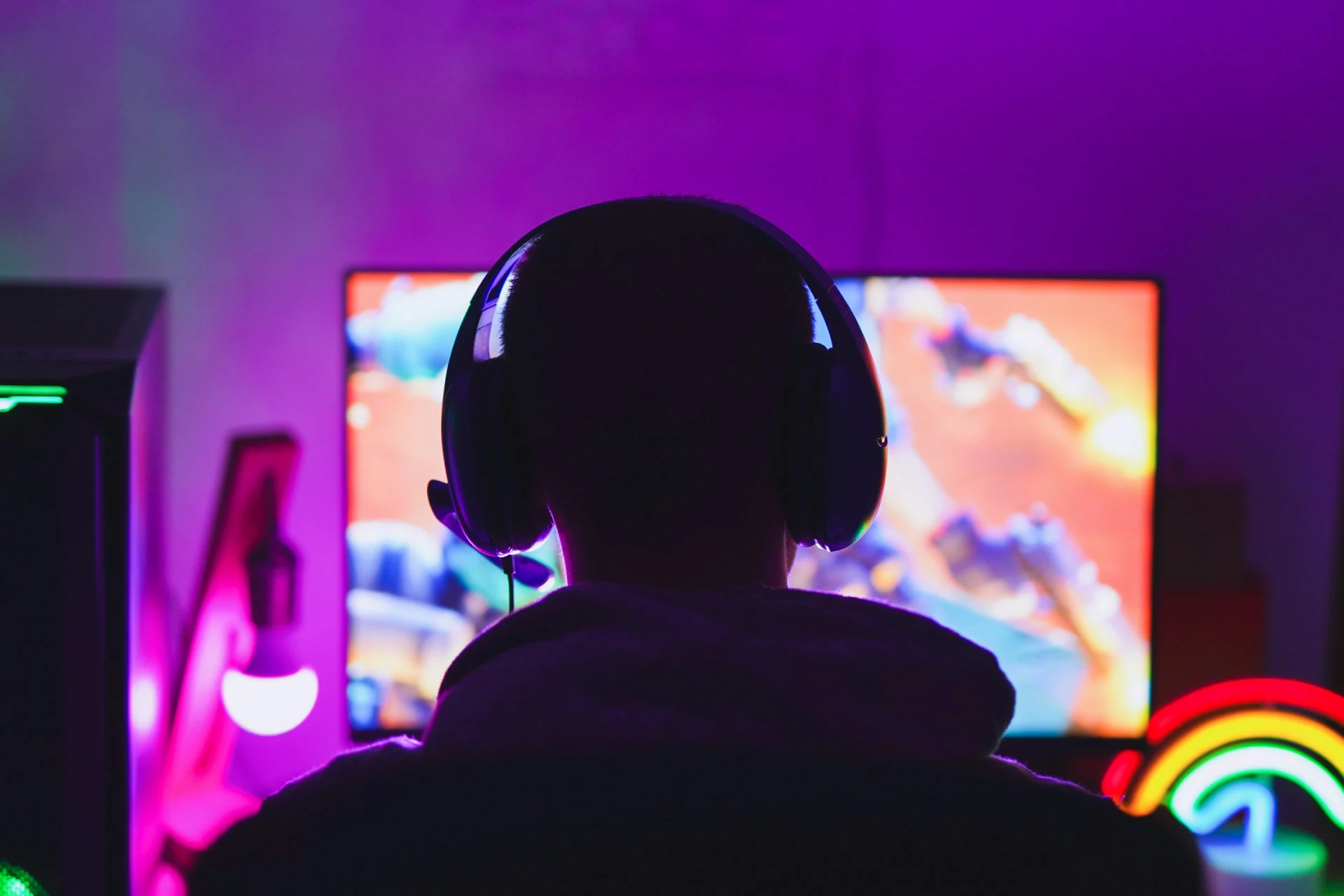 Gamer wearing headphones focused on gameplay on a computer screen