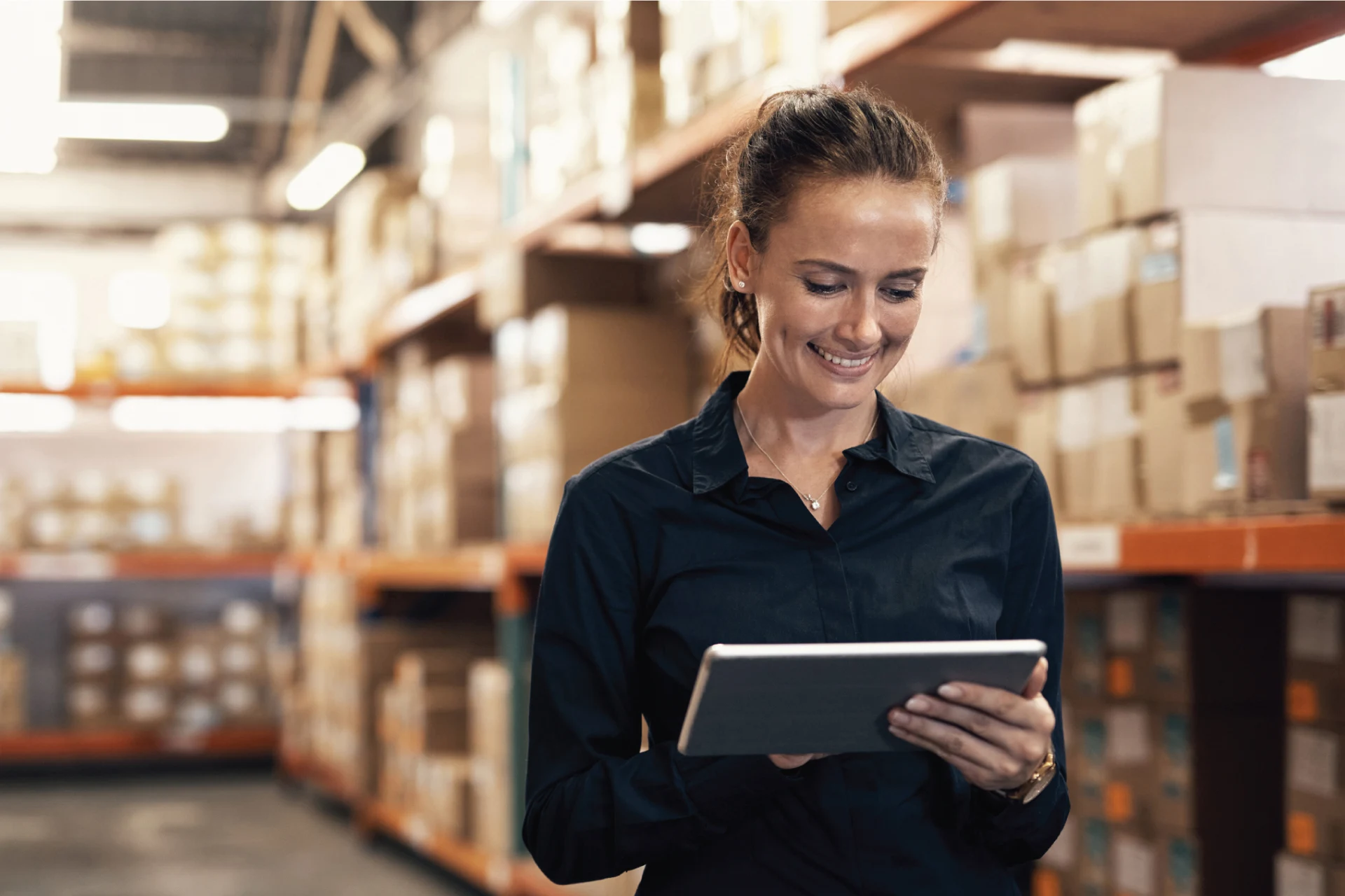 Professional using a tablet in a warehouse filled with boxes