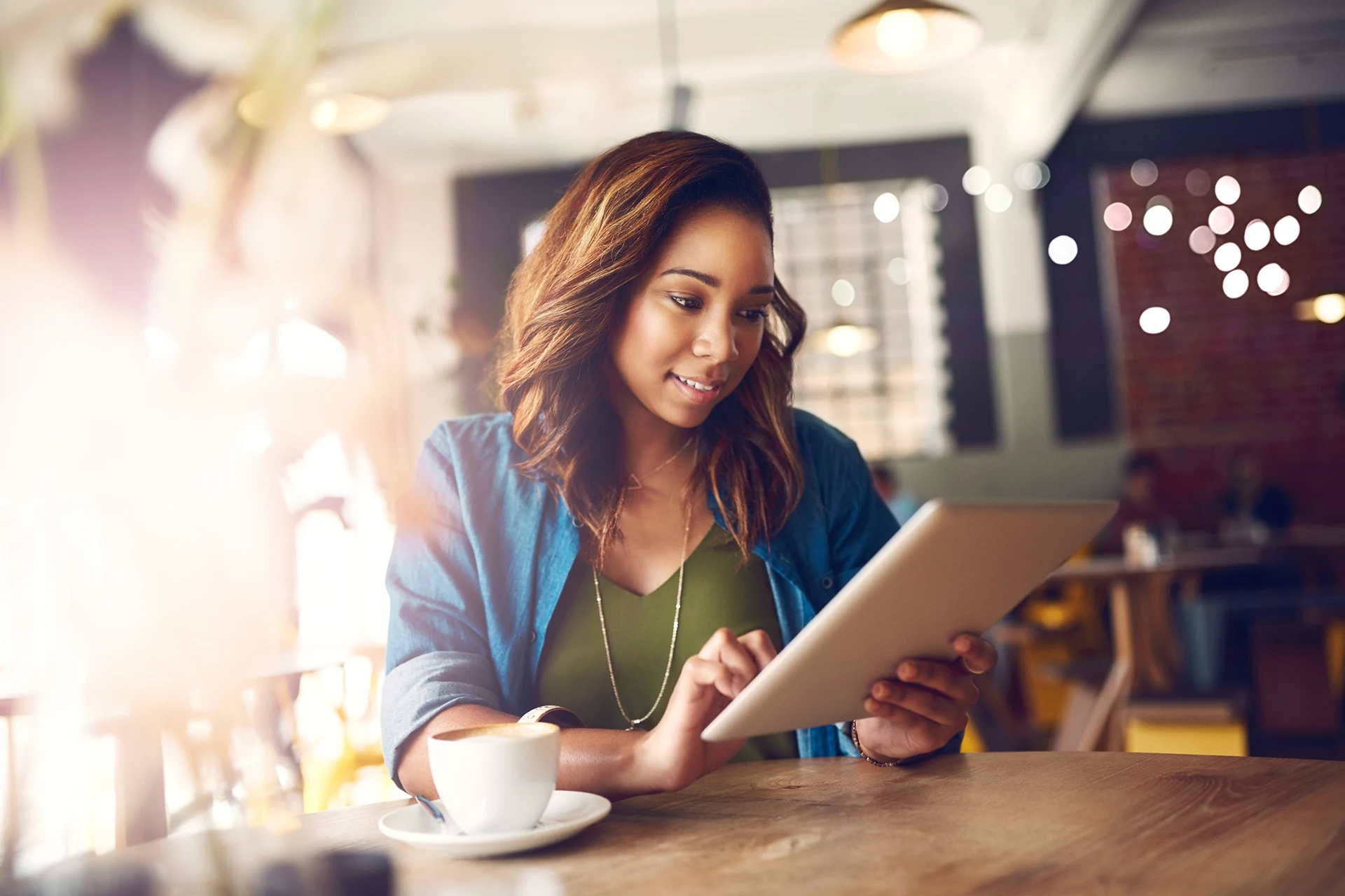 Person using a tablet while enjoying coffee in a cafe setting