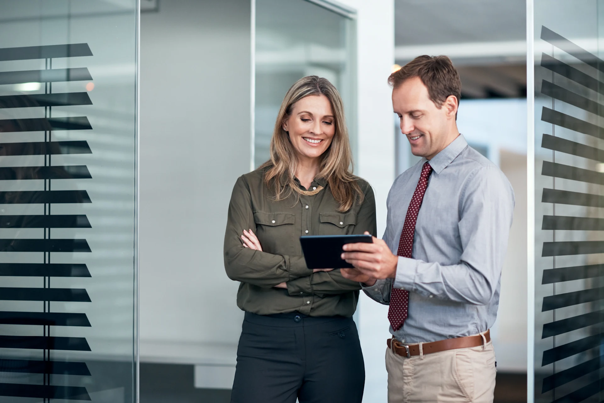 Two professionals discussing solutions while reviewing a tablet