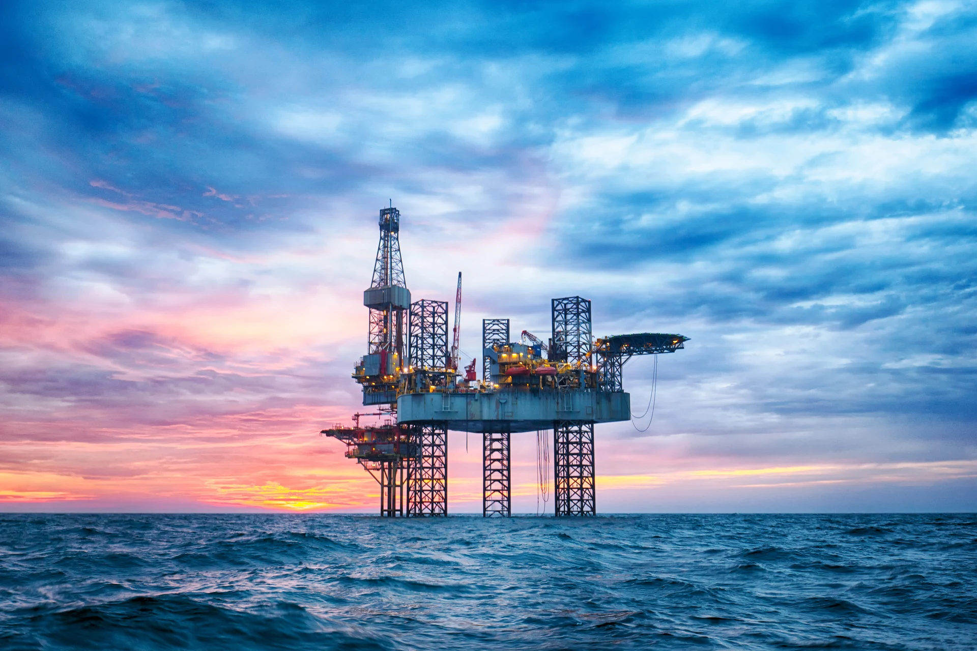 Oil rig in the ocean at sunset representing enterprise solutions